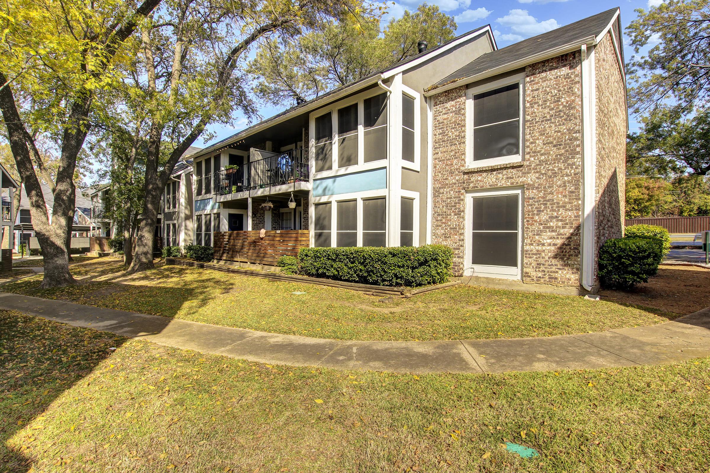 a large brick building with grass in front of a house