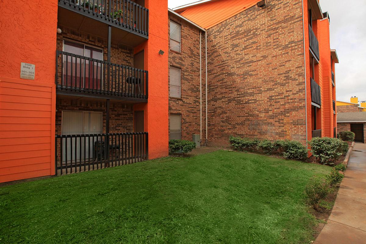 a large brick building with grass in front of a house