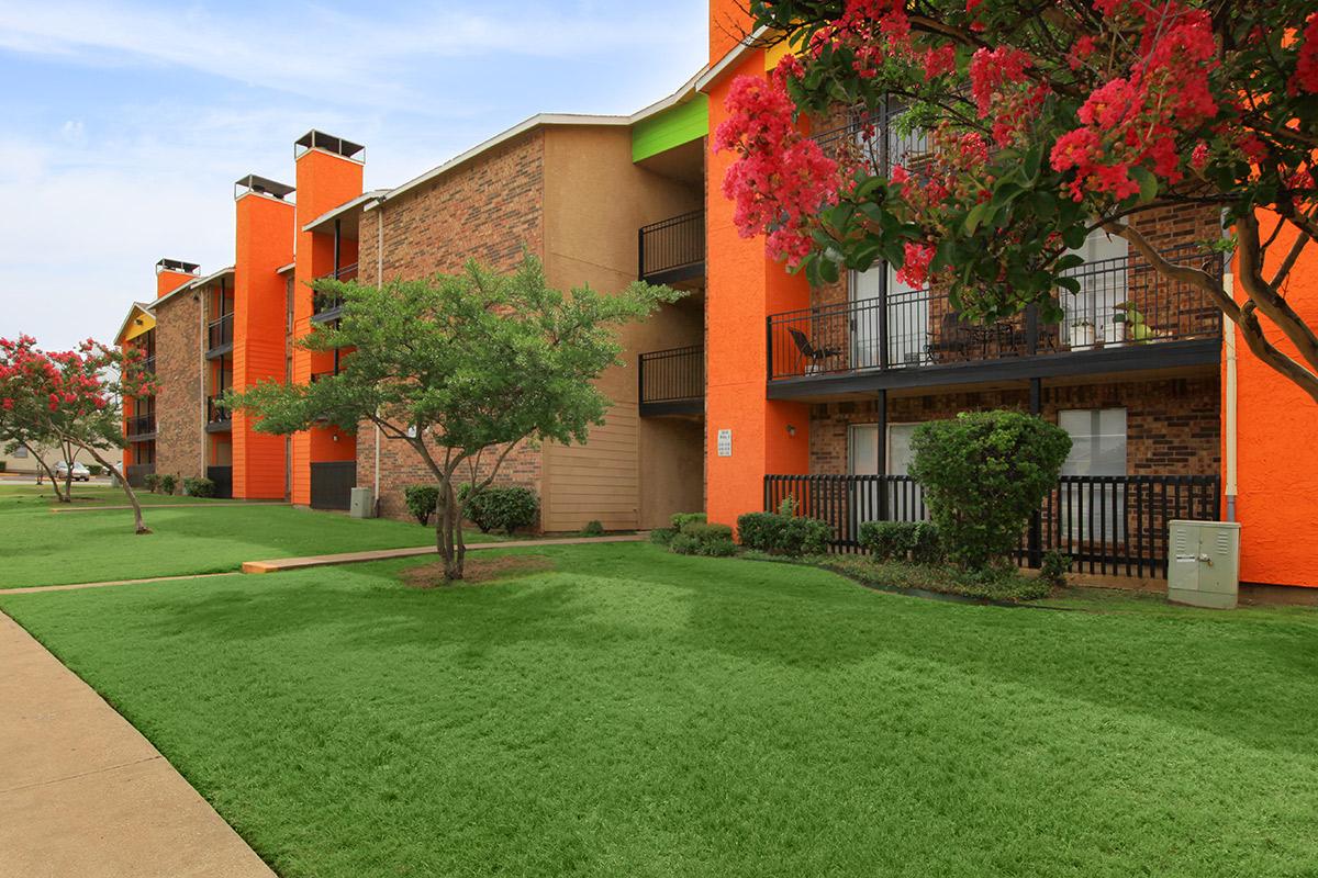 a large brick building with green grass