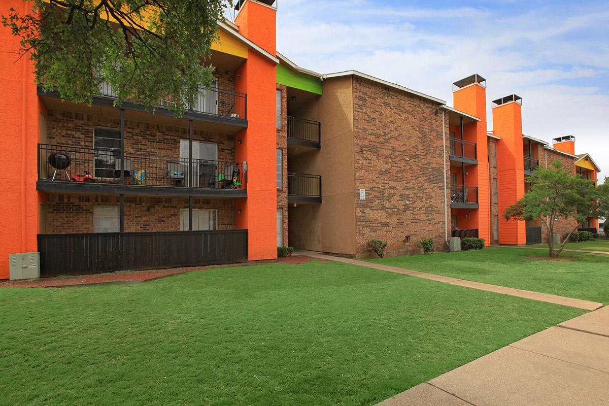 a large brick building with grass in front of a house