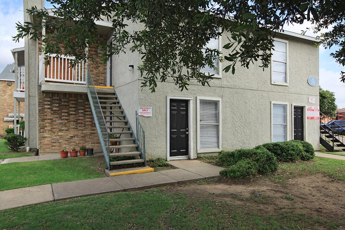 a large brick building with grass in front of a house