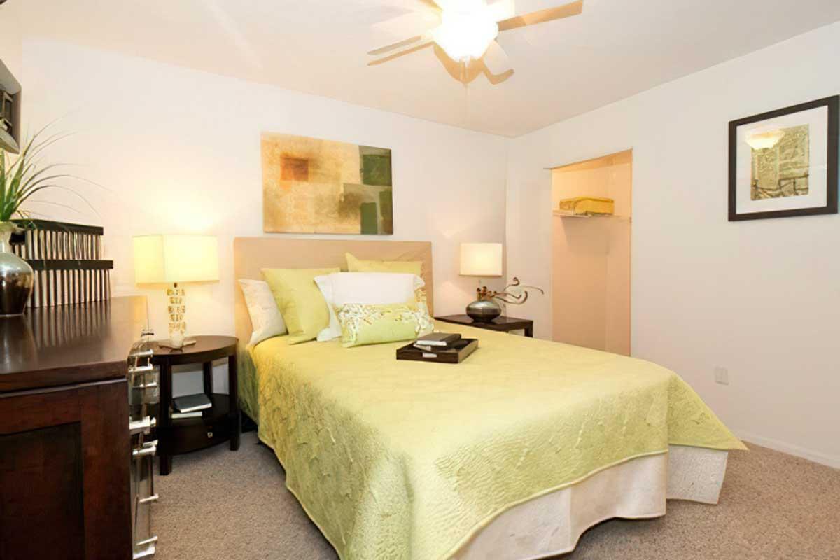 A cozy bedroom featuring a queen-sized bed with a light green quilt and decorative pillows.