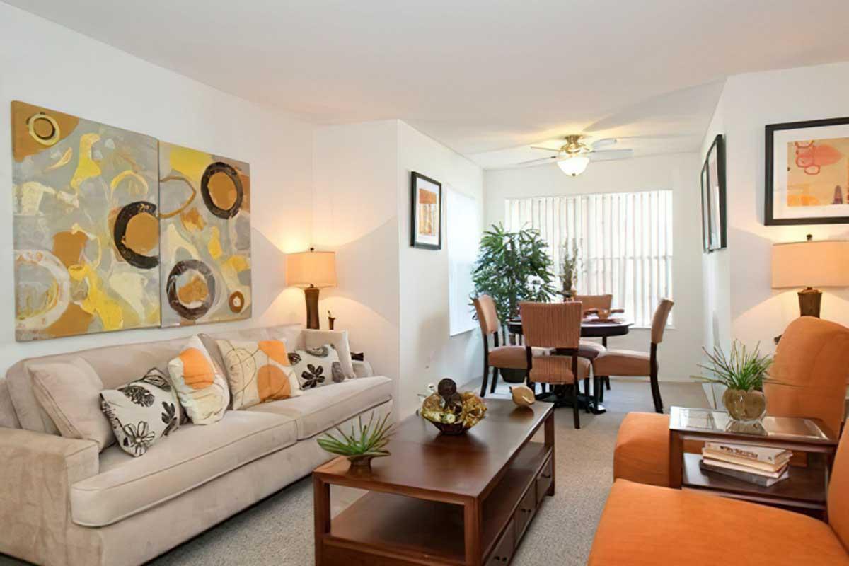 Cozy living room featuring a light-colored sofa adorned with decorative pillows, a wooden coffee table, and a potted plant.