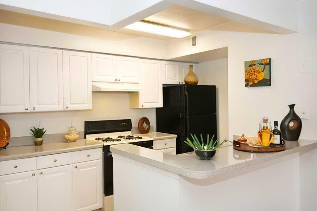 A modern kitchen featuring white cabinets, a black refrigerator, and a stove.