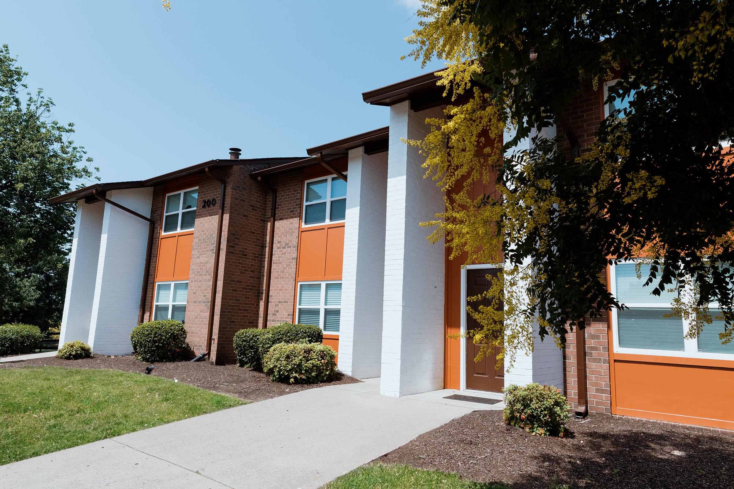 a house with bushes in front of a brick building