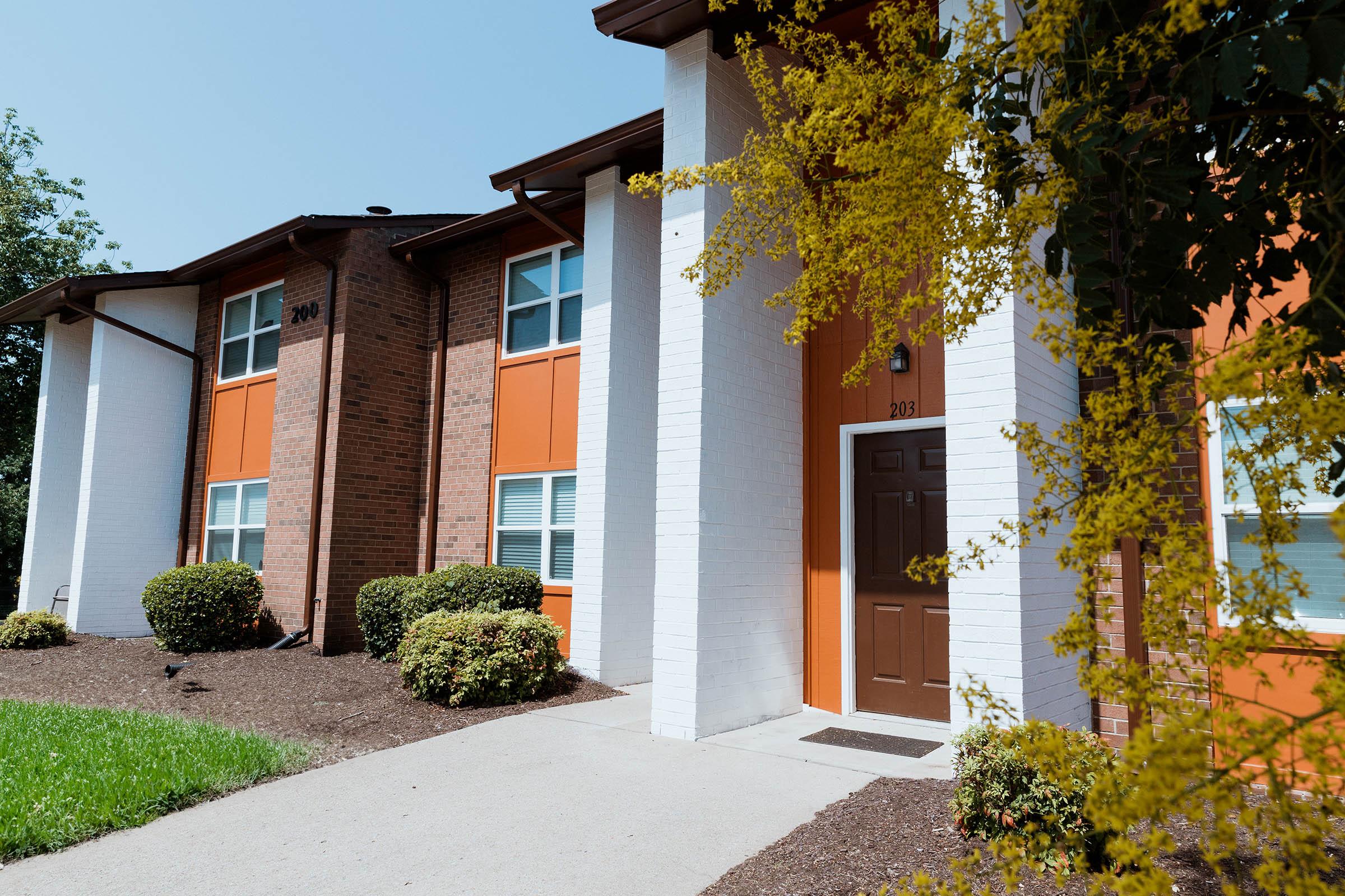 a house with bushes in front of a brick building