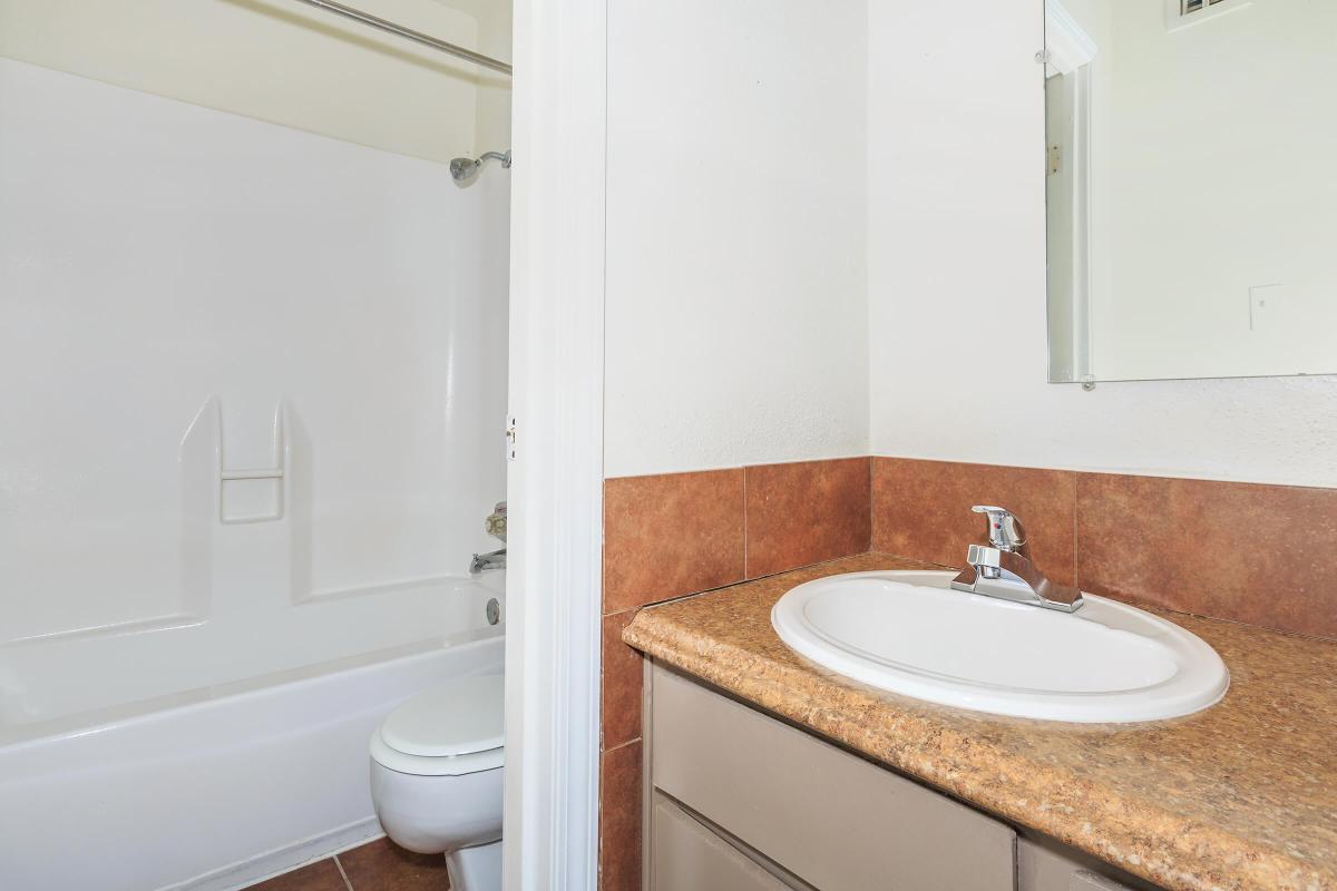 a white sink sitting under a mirror