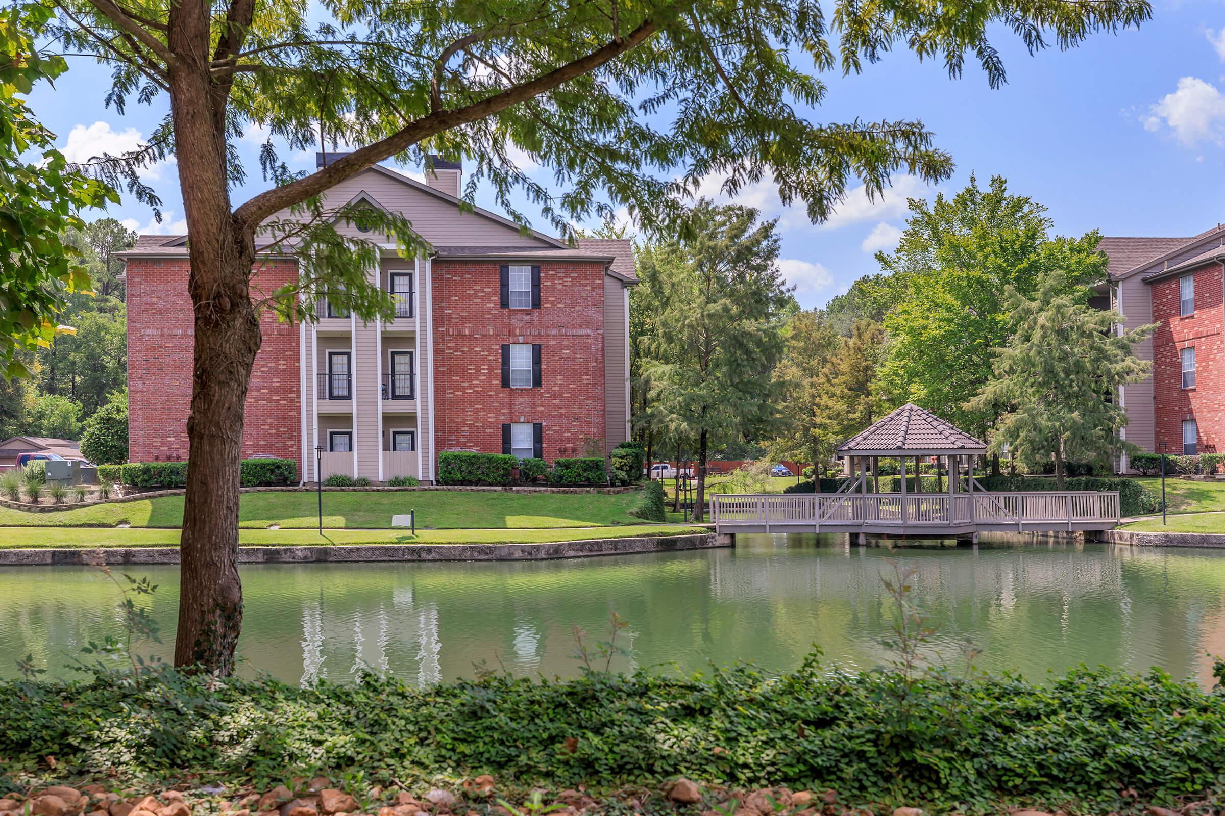 a large brick building with a pond in front of a house