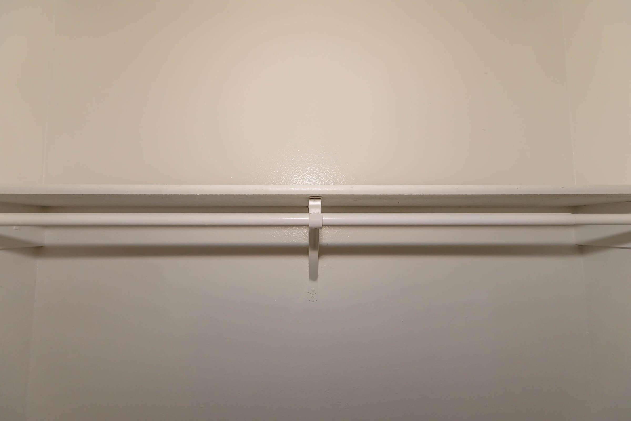 Empty closet interior with smooth white walls and a single shelf above a hanging rod. The space is clean and minimalistic, providing a blank canvas for storage or organization.