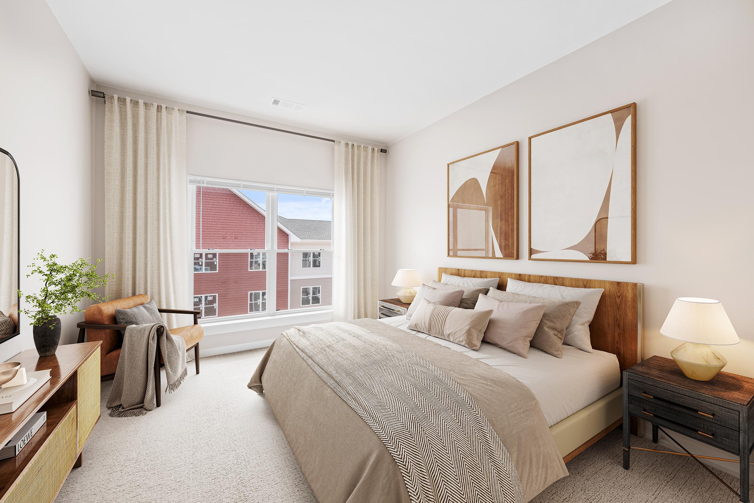 A cozy bedroom featuring a wooden bed with neutral-toned bedding and decorative pillows. An inviting armchair is in the corner, alongside a minimalist wooden nightstand with a lamp. Large windows dressed with light curtains allow natural light, while abstract wall art enhances the serene atmosphere.