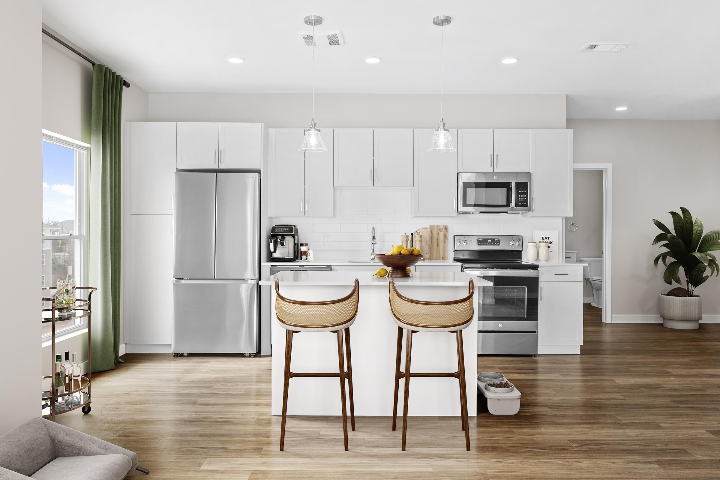 Modern kitchen featuring white cabinetry, stainless steel appliances, and a large island with two bar stools. Natural light fills the space from a window, and there are green curtains. A potted plant and a small bar cart add to the décor, creating a bright and inviting atmosphere.