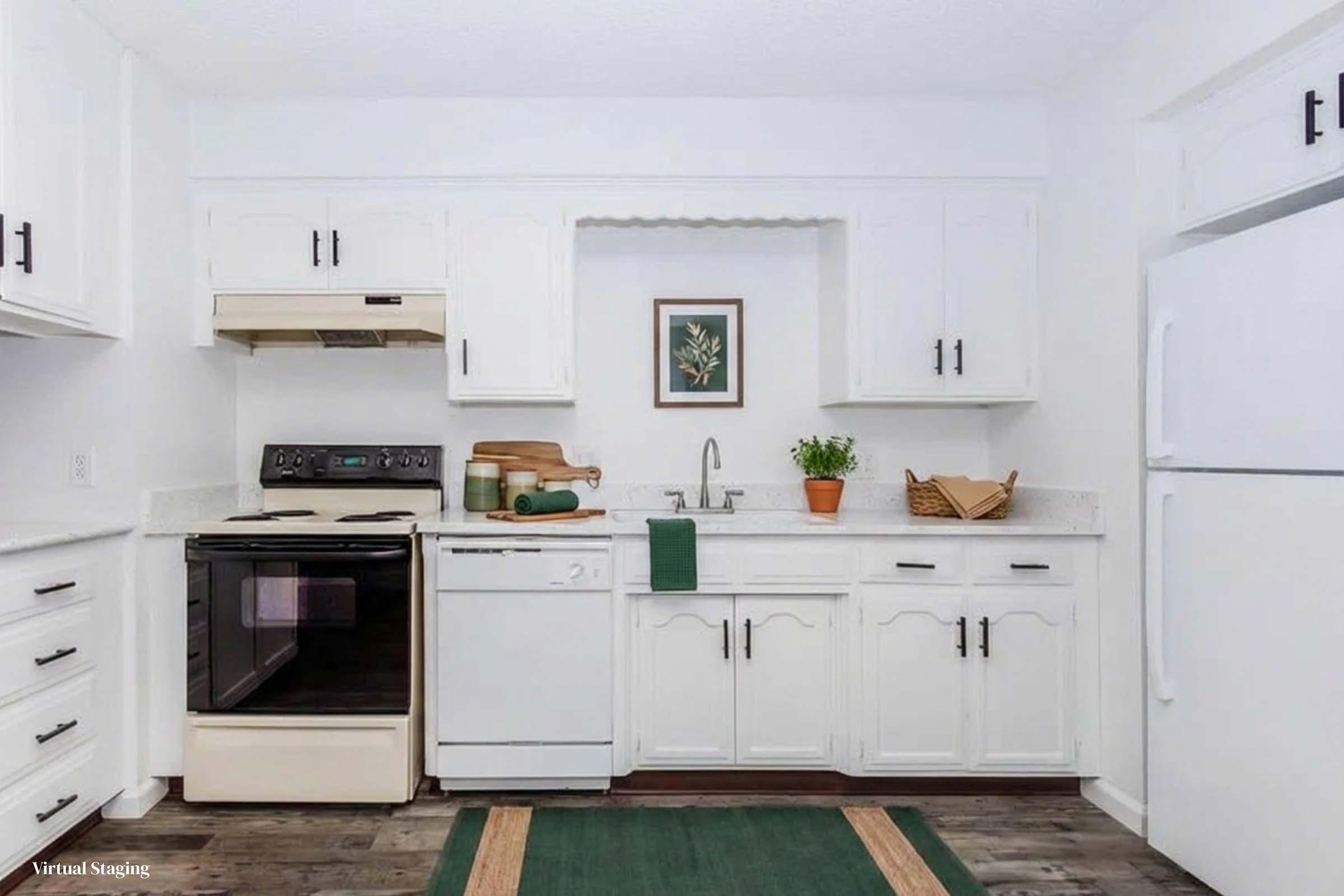 A bright and modern kitchen featuring white cabinets, a black stove, and a dishwasher. The countertop is light with a small window displaying a potted plant. A green rug is placed on the floor, and a wooden bowl sits on the counter. The overall decor is clean and inviting, promoting a spacious feel.