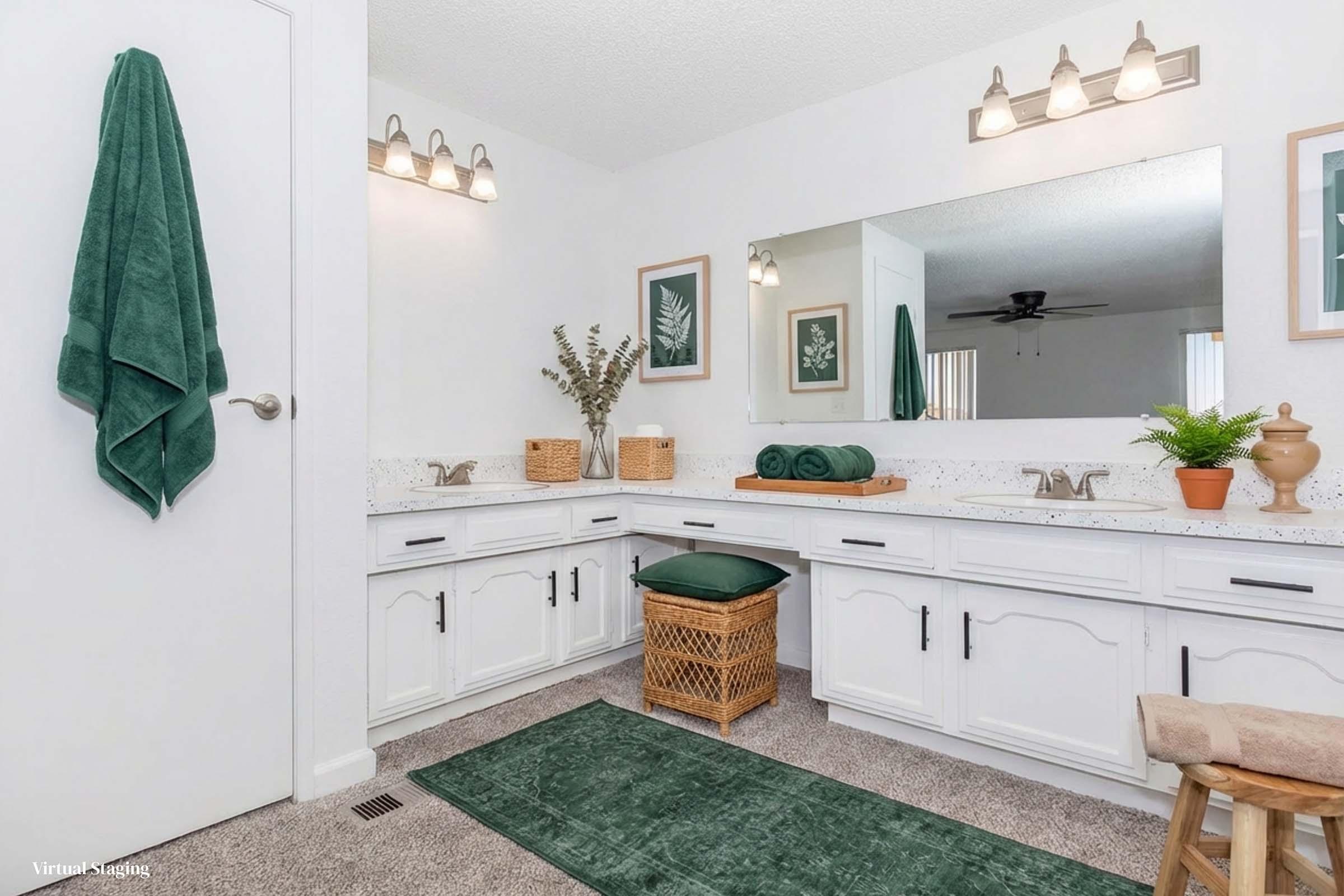 A modern bathroom featuring a double sink vanity with white cabinetry, a large mirror, and decorative plants. Soft green towels are neatly arranged, and a woven basket sits on the floor. A green bath mat complements the decor, and natural light fills the space, creating a fresh and inviting atmosphere.