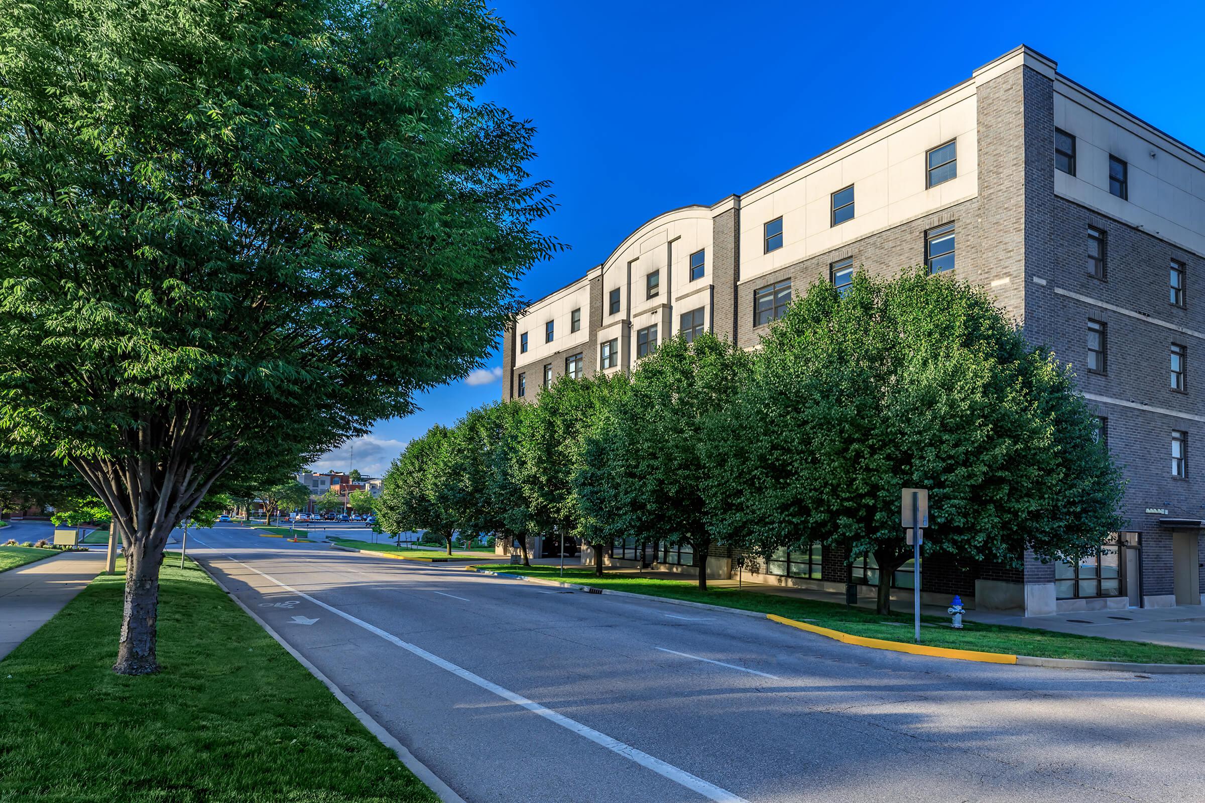 an empty road with trees on the side of a building