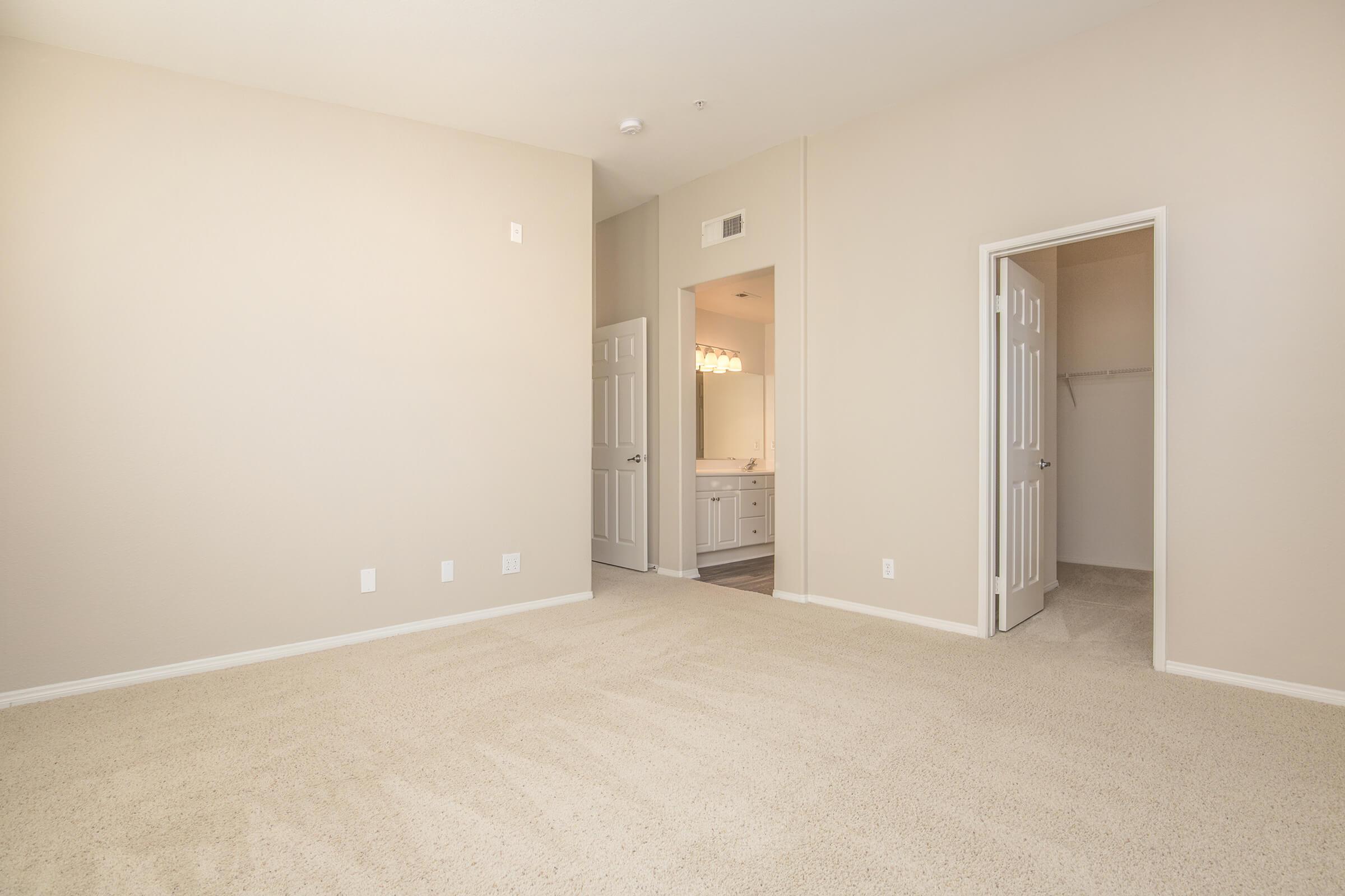 Bedroom with open bathroom and closet doors