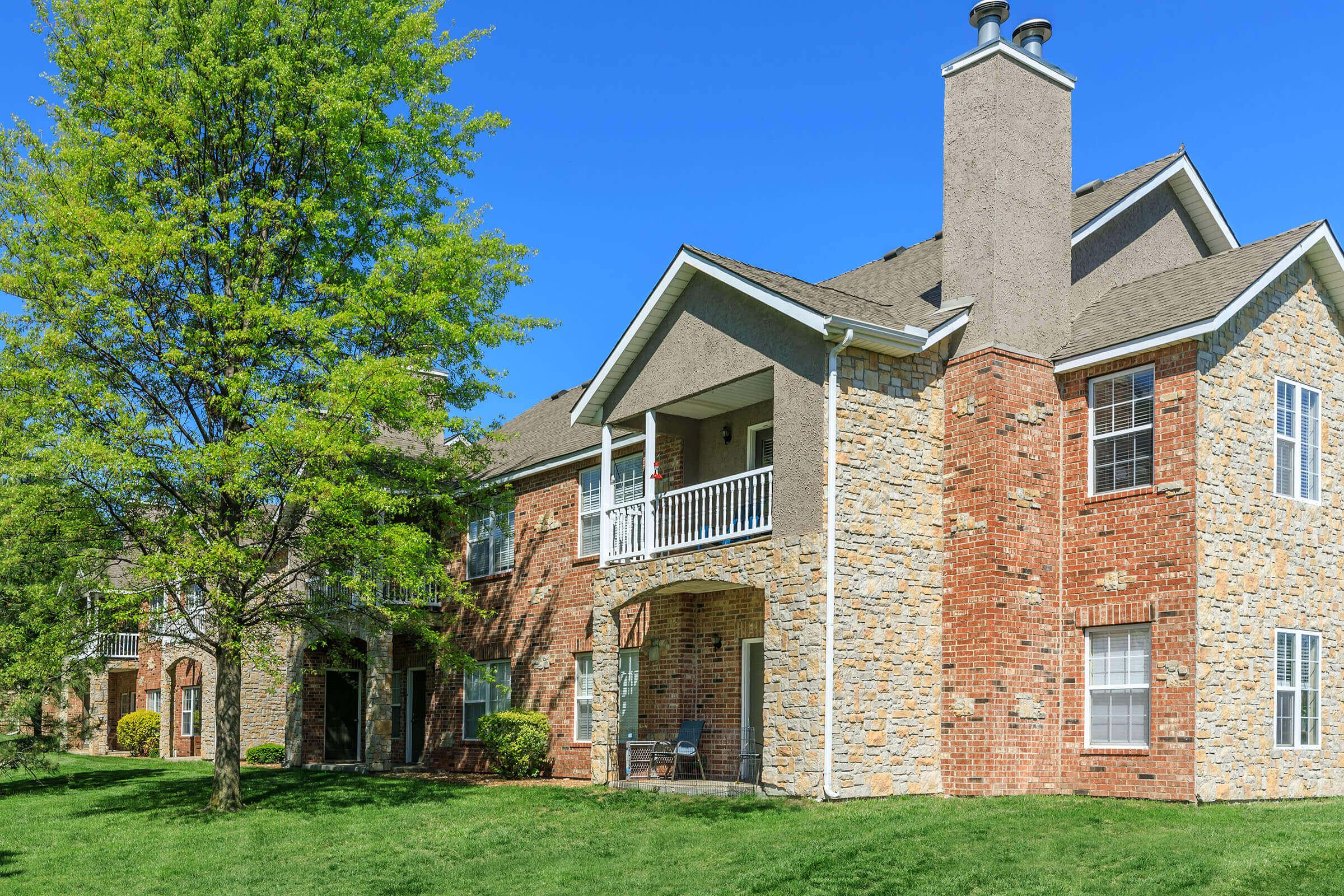 a large brick building with grass in front of a house