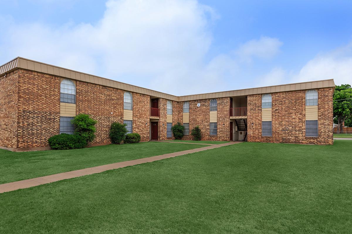 a large brick building with grass in front of a house