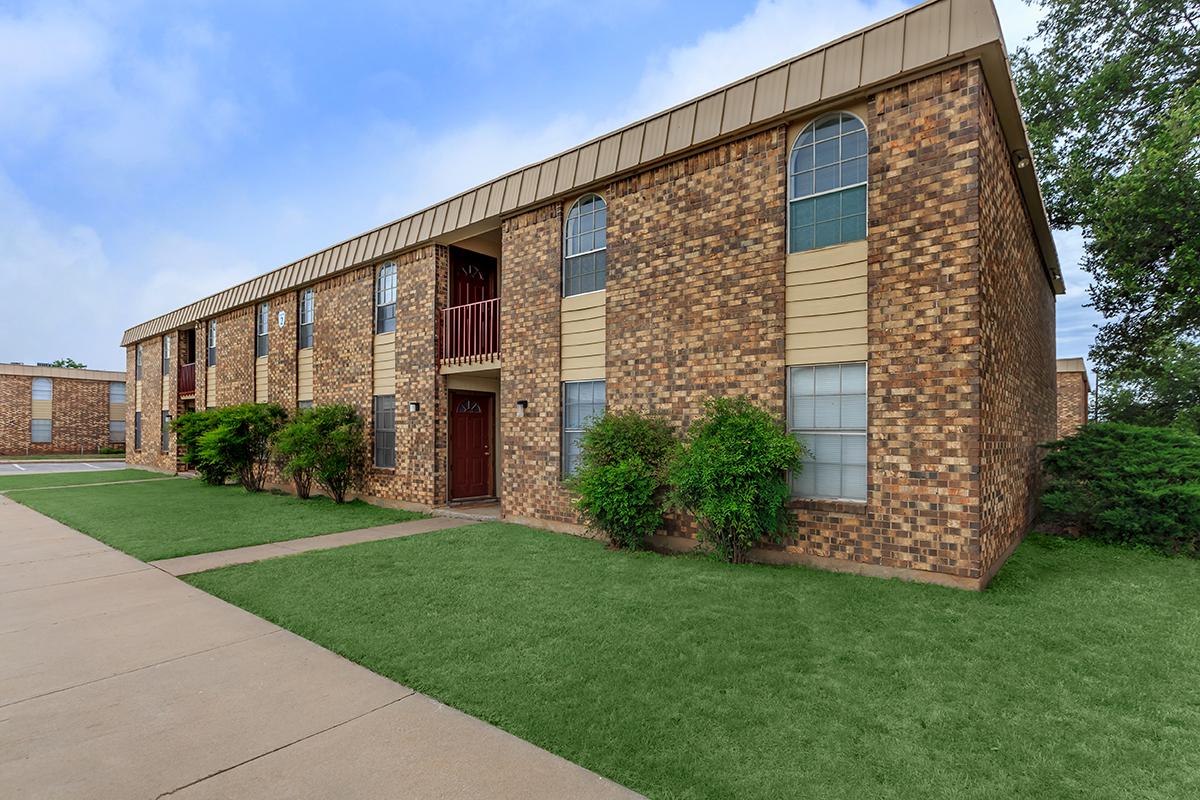 a large brick building with grass in front of a house