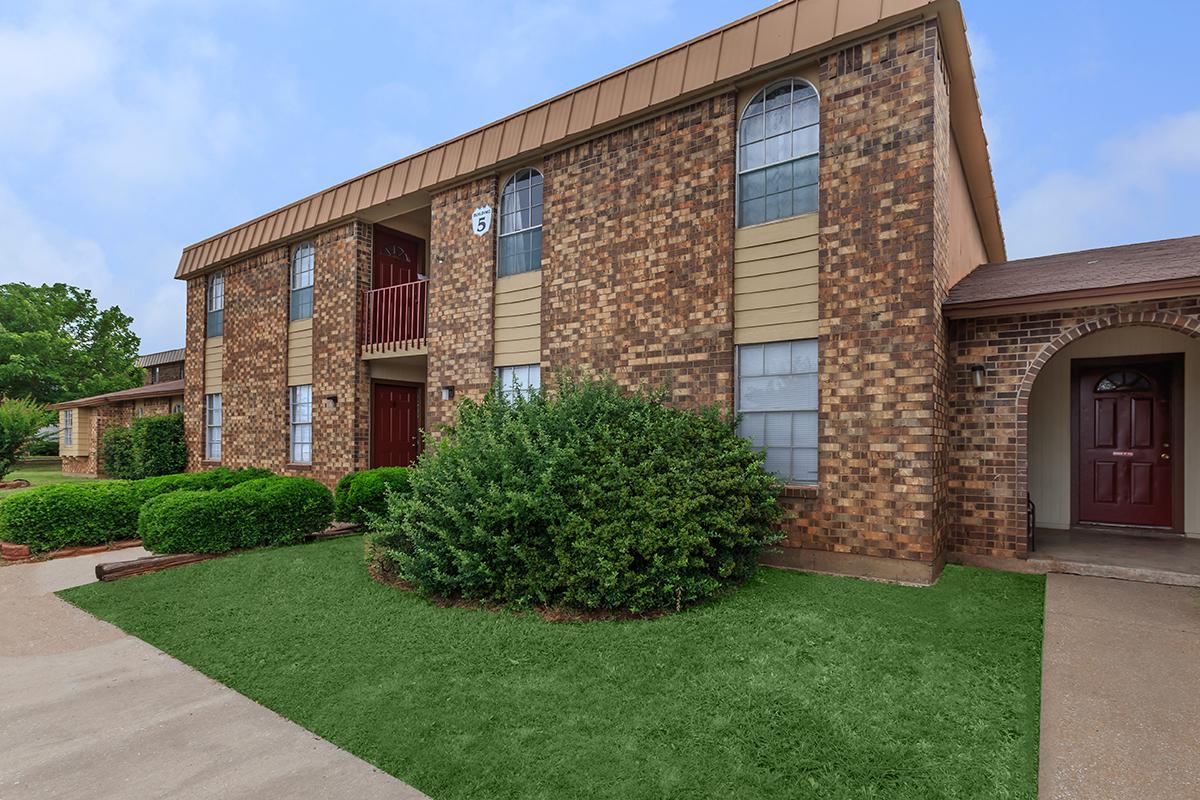 a large brick building with grass in front of a house