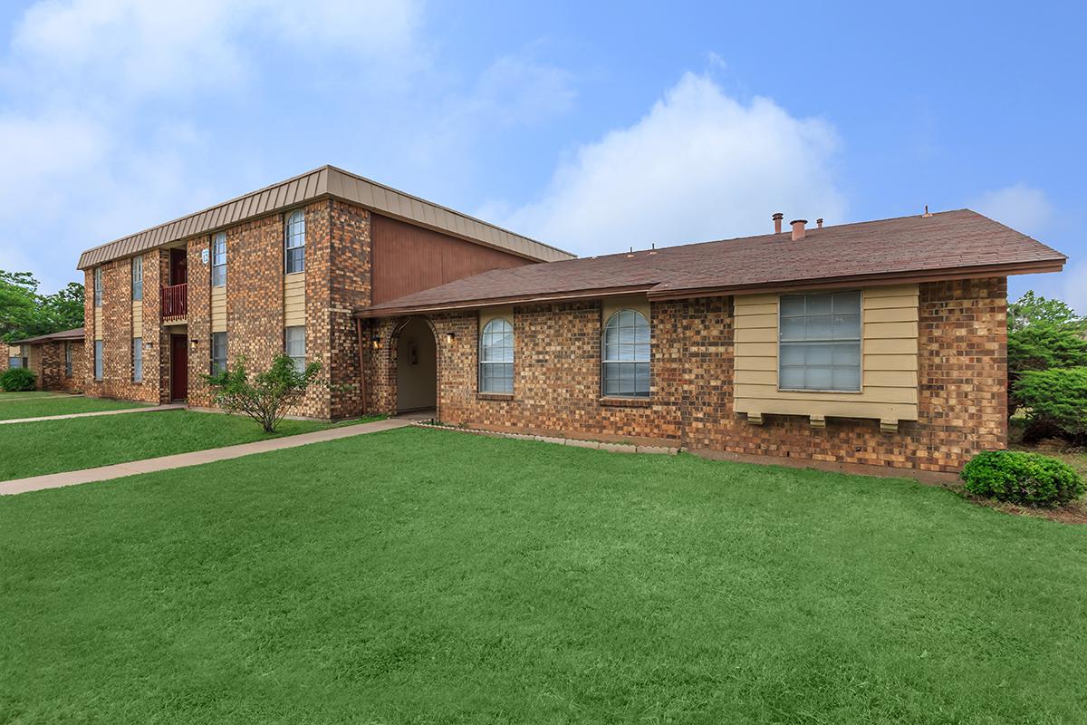 a large brick building with grass in front of a house