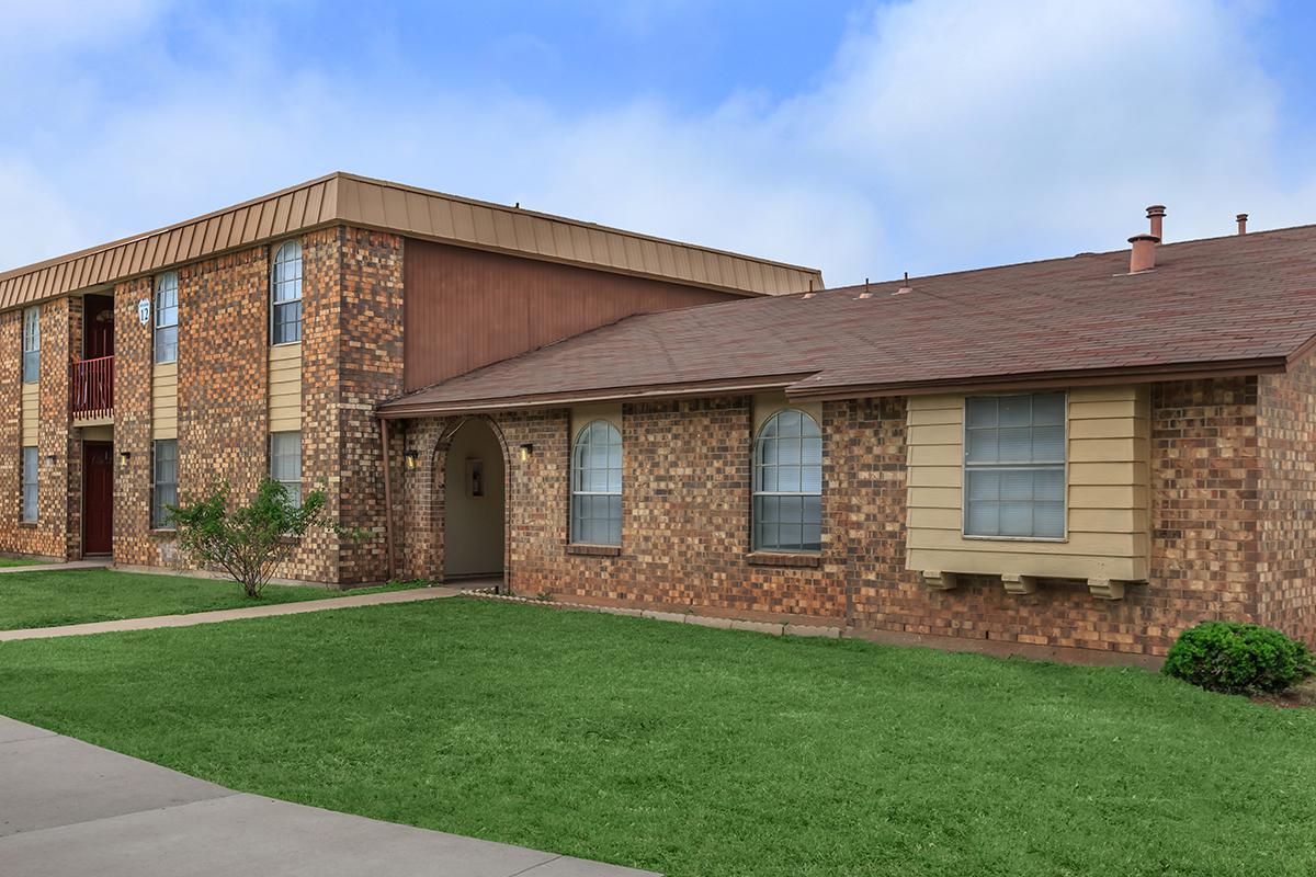 a large brick building with grass in front of a house