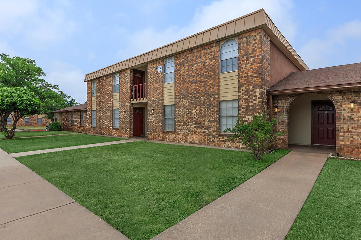 a large brick building with grass in front of a house