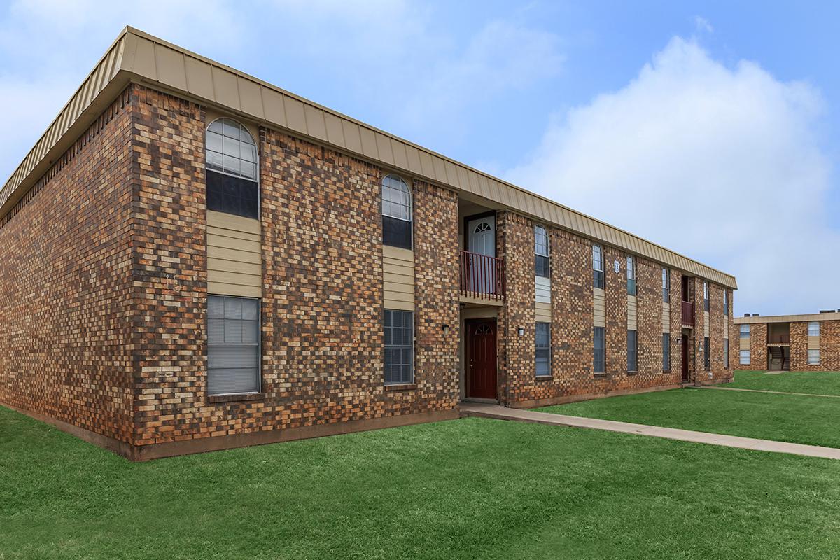 a large brick building with a grassy field