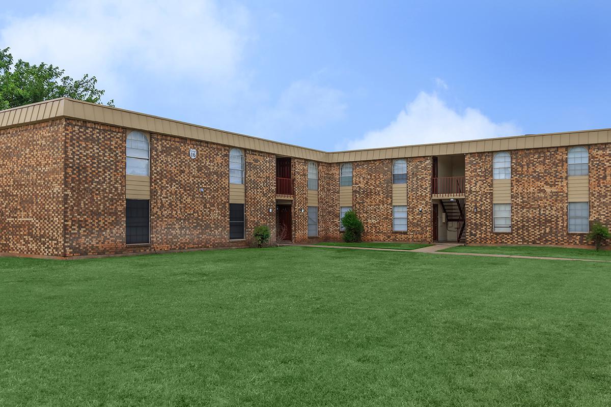 a large brick building with green grass