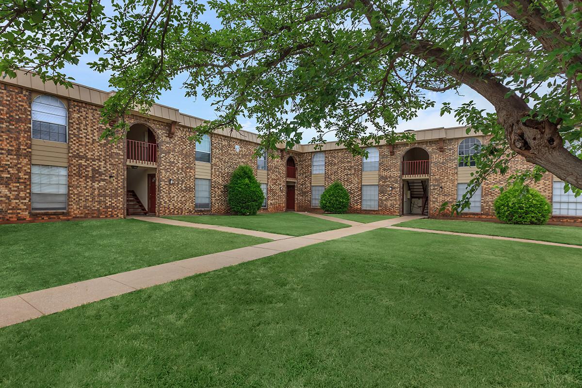 a house with a lawn in front of a brick building