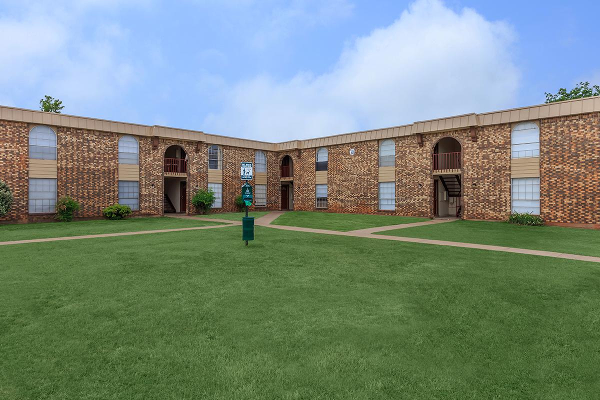 a large brick building with green grass