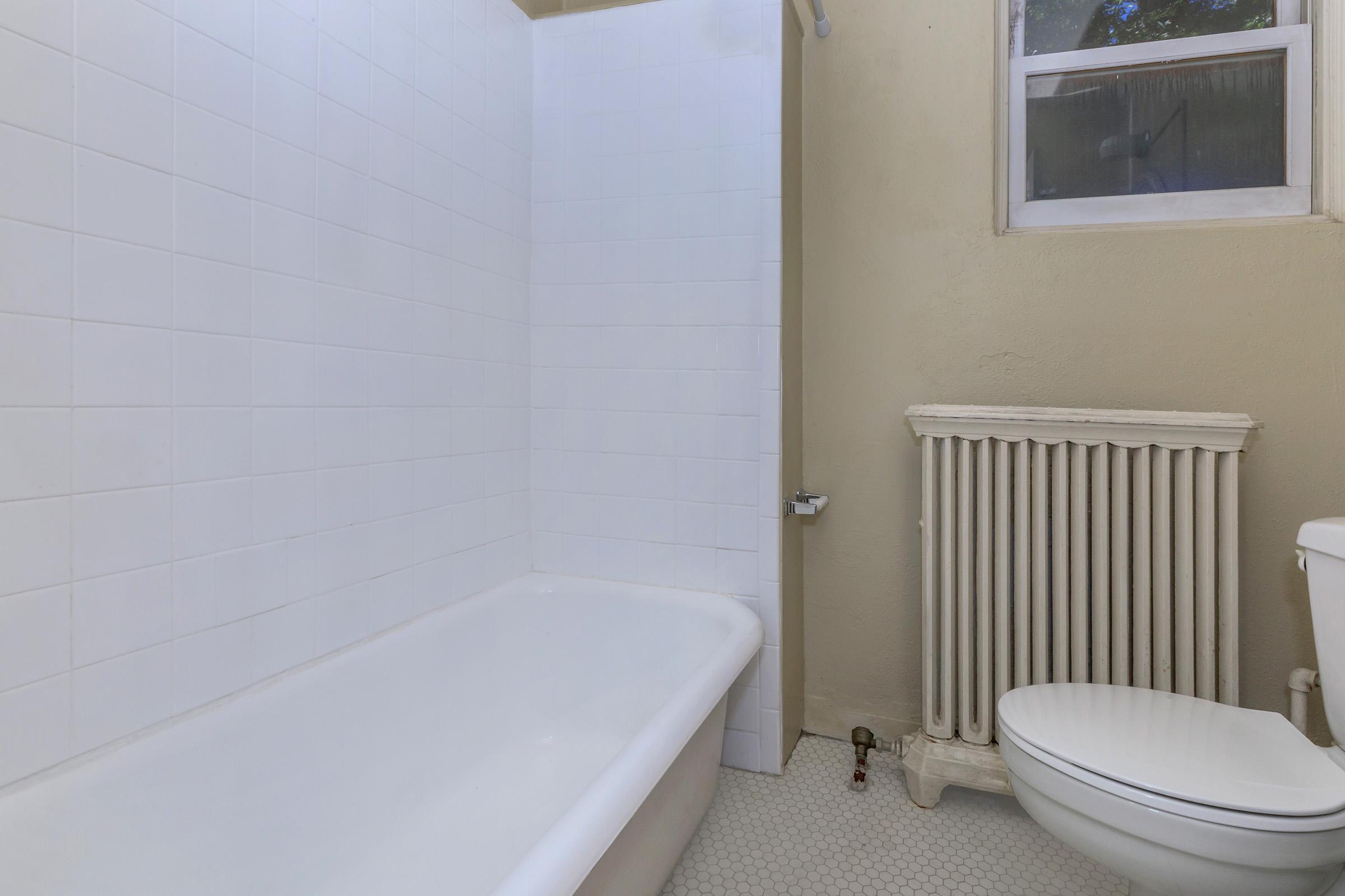 a room with a sink and a white tub sitting next to a window