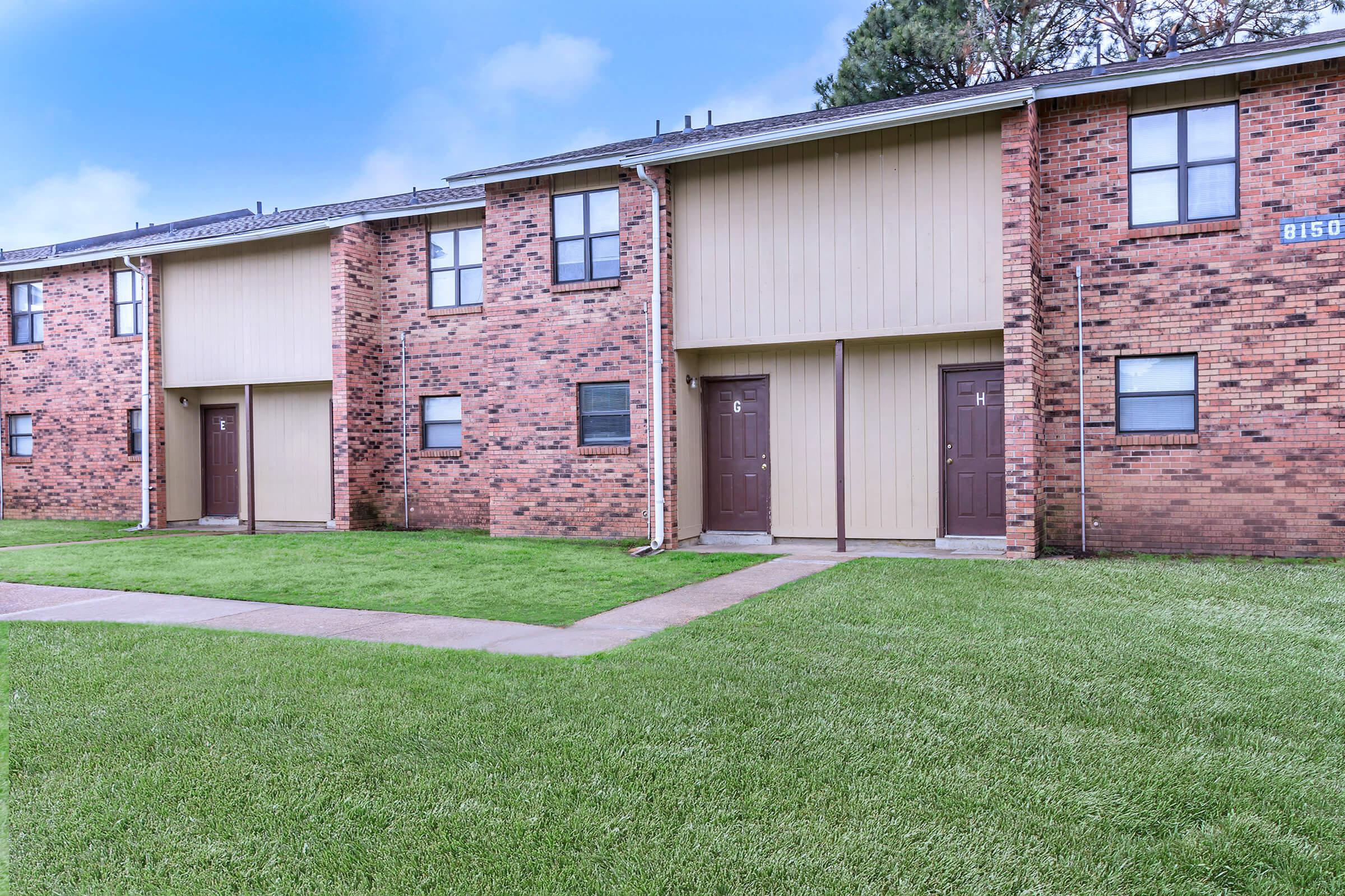 a house with a lawn in front of a brick building