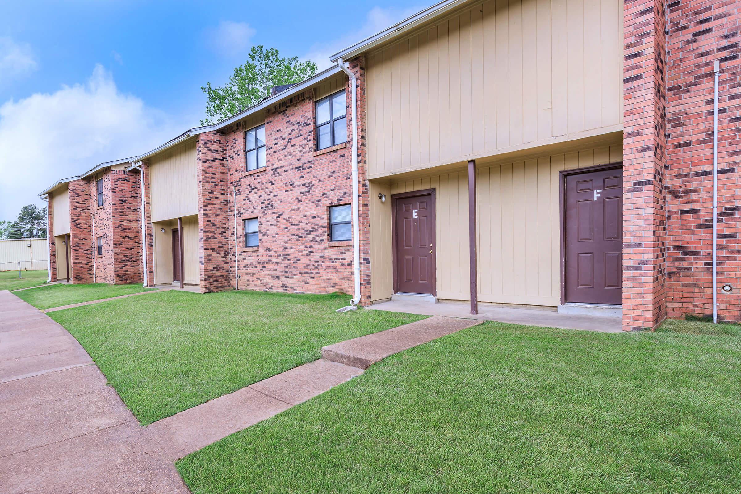 a large brick building with grass in front of a house