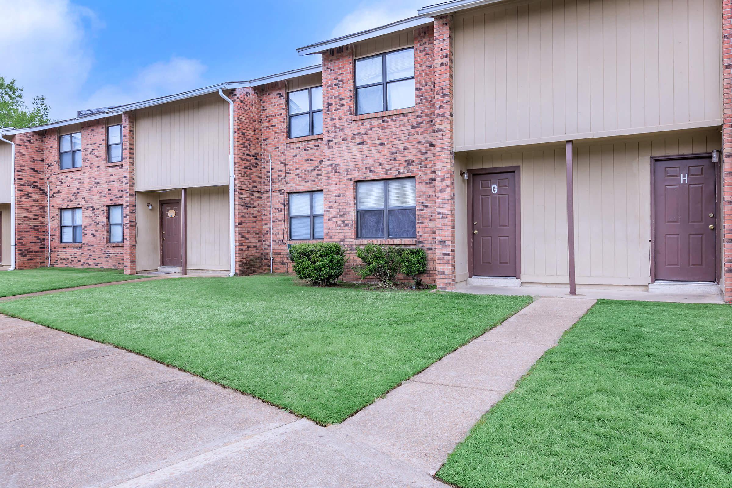 a large brick building with grass in front of a house