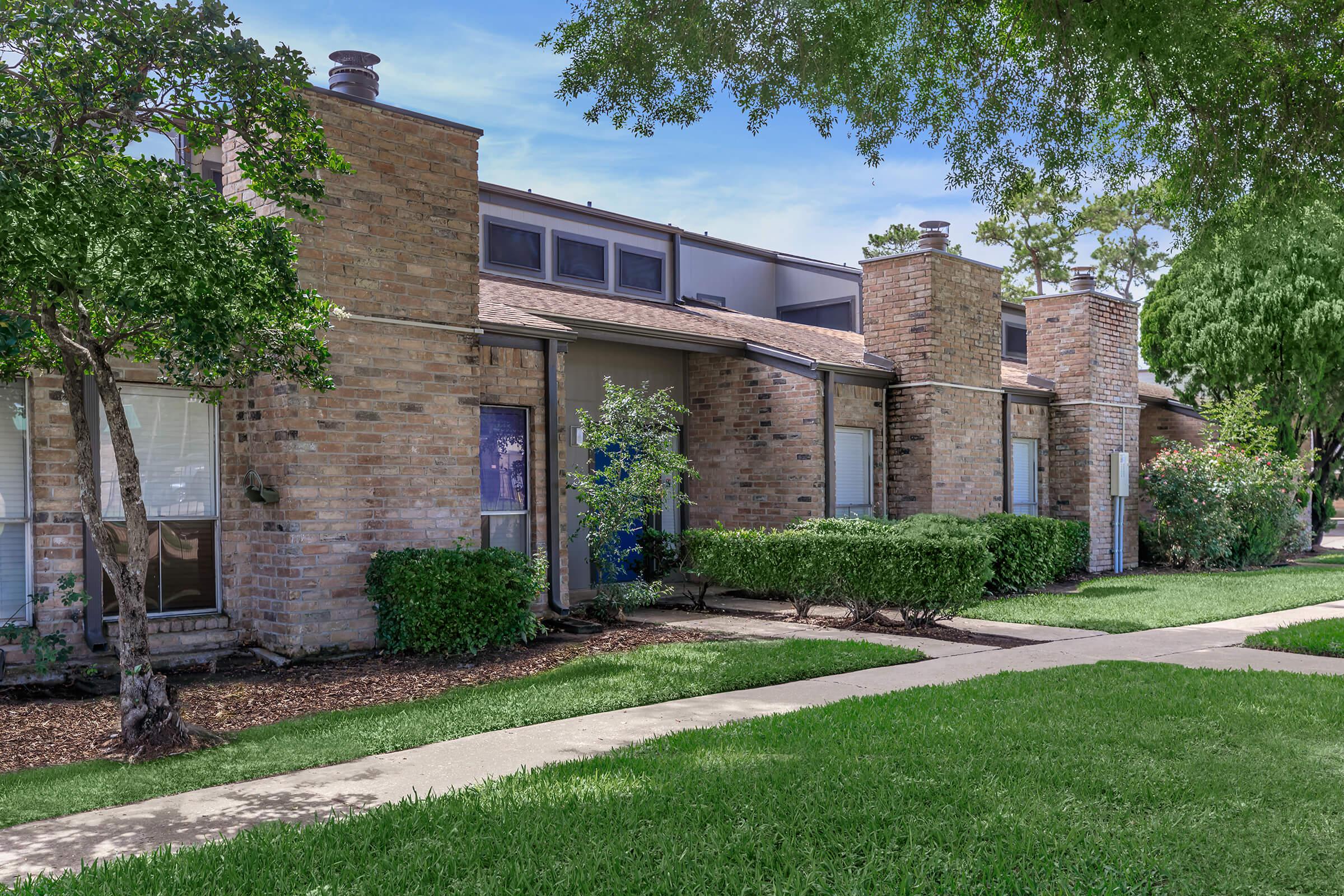 a large brick building with grass in front of a house