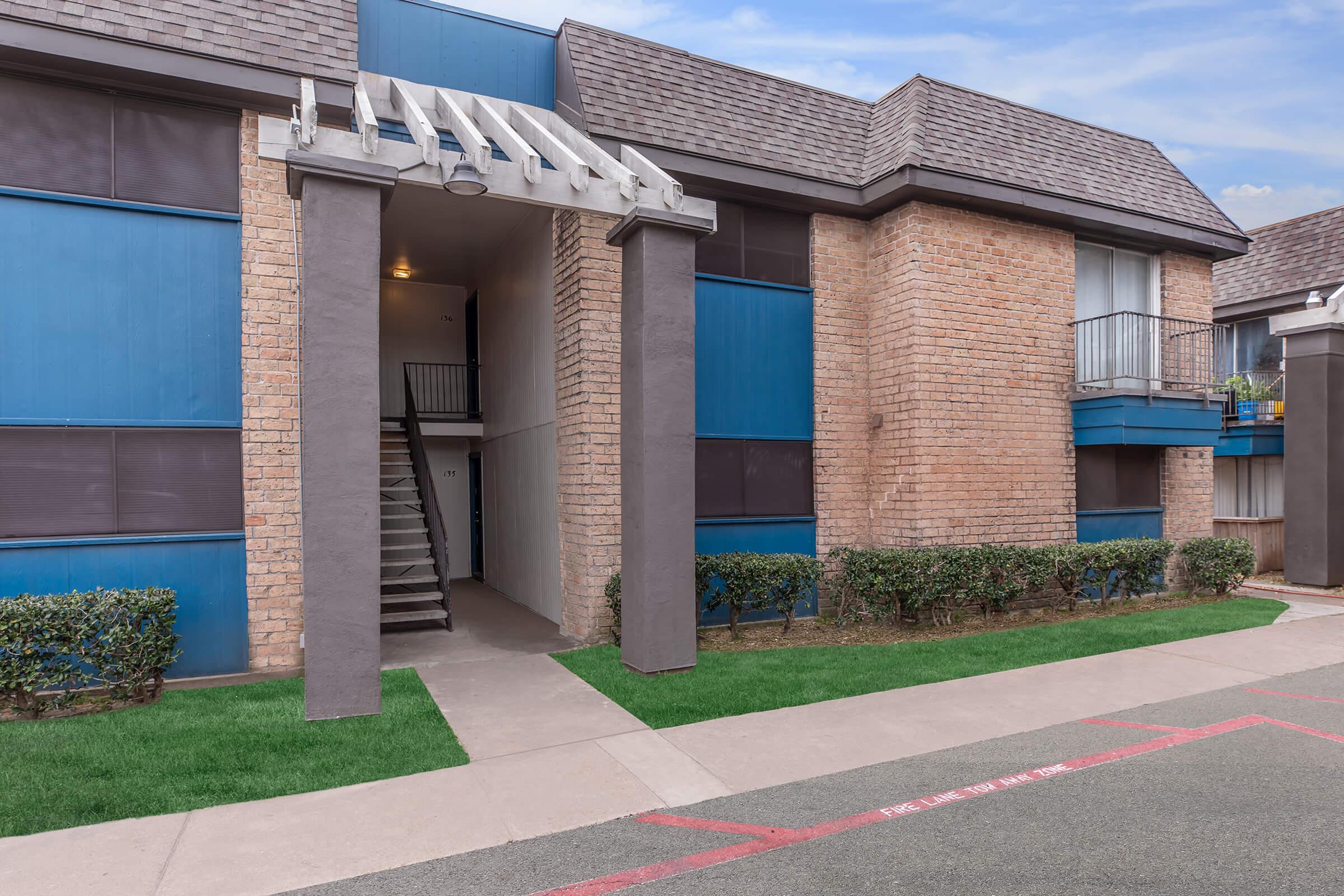 a large brick building with grass in front of a house