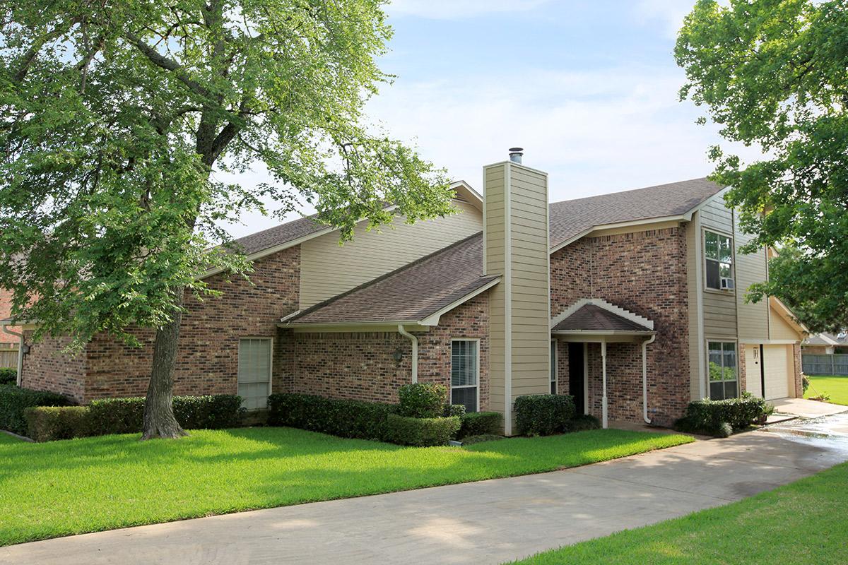 a large brick building with grass in front of a house