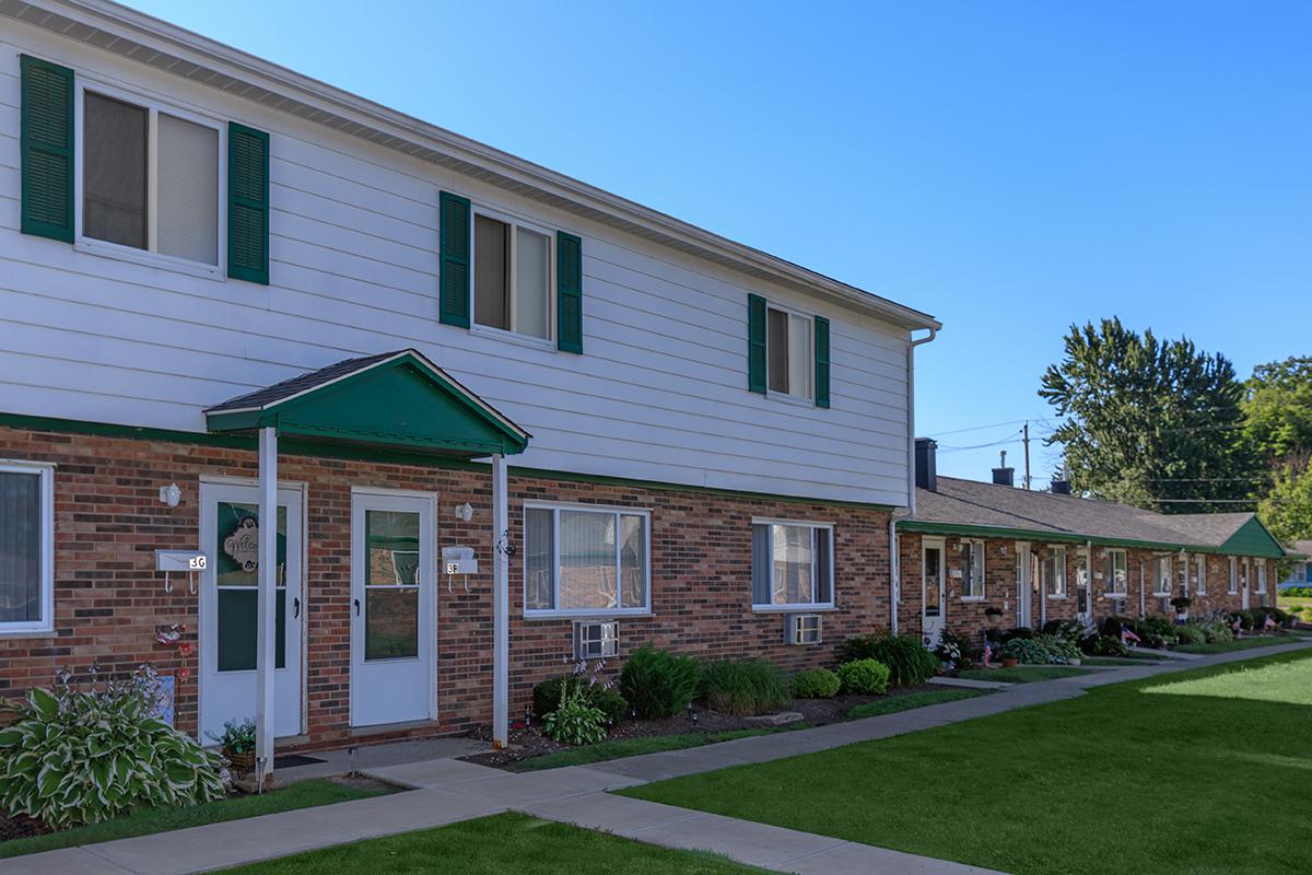 a large brick building with grass in front of a house