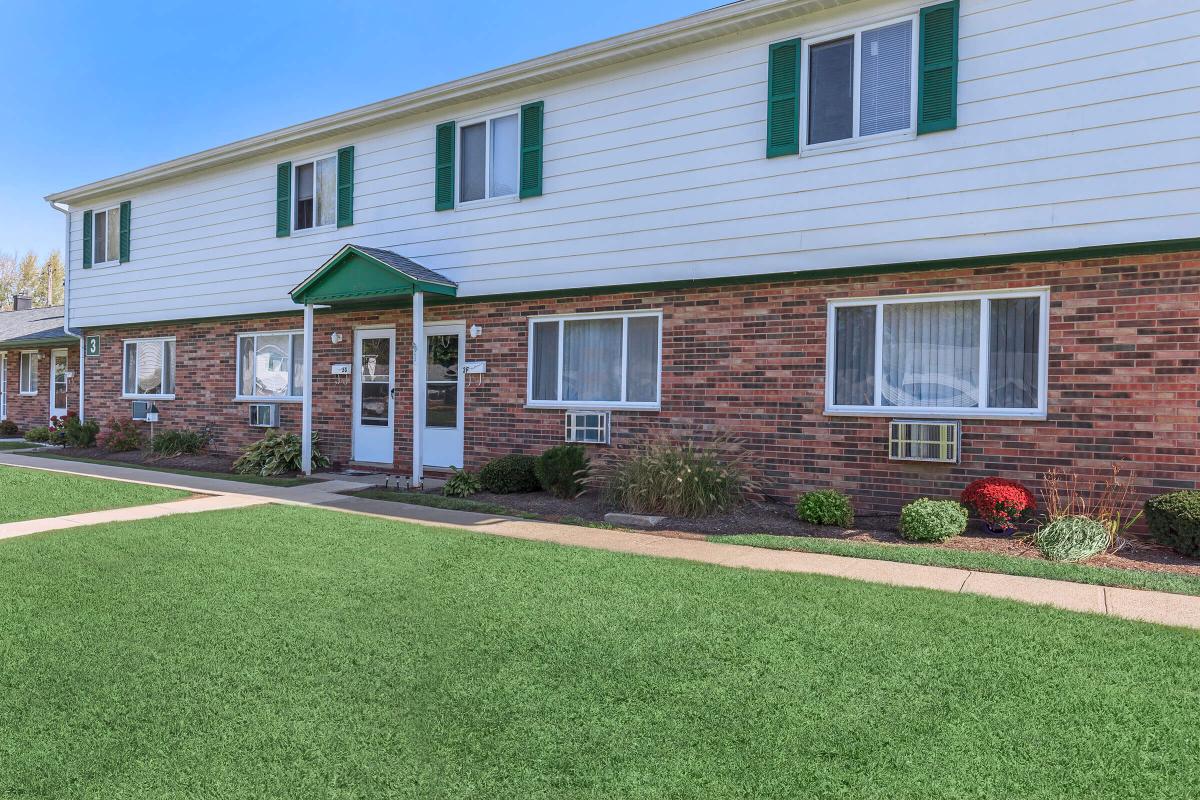 a house with a lawn in front of a brick building