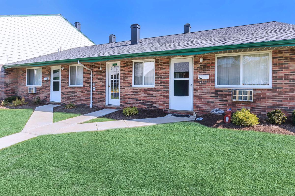 a house with a lawn in front of a brick building