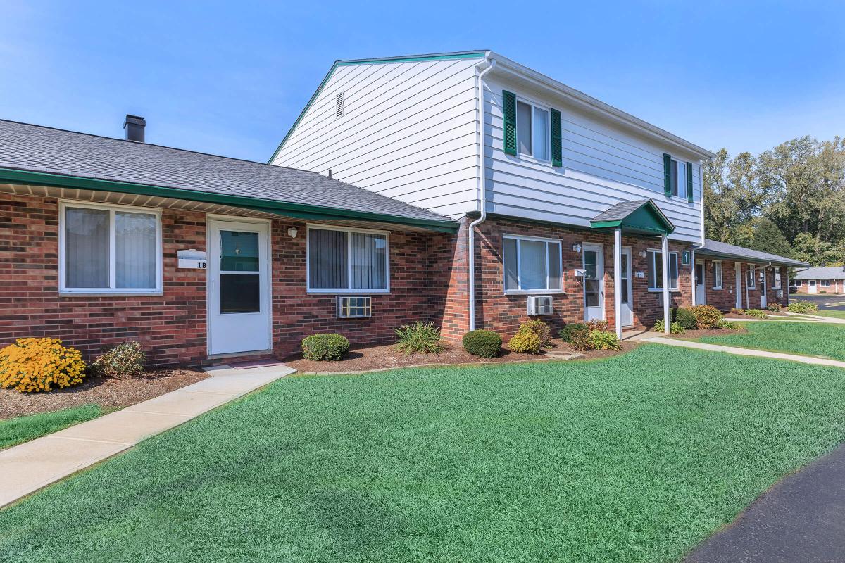 a house with a lawn in front of a brick building