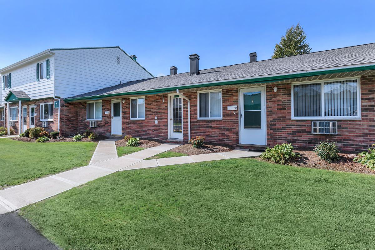 a house with a lawn in front of a brick building