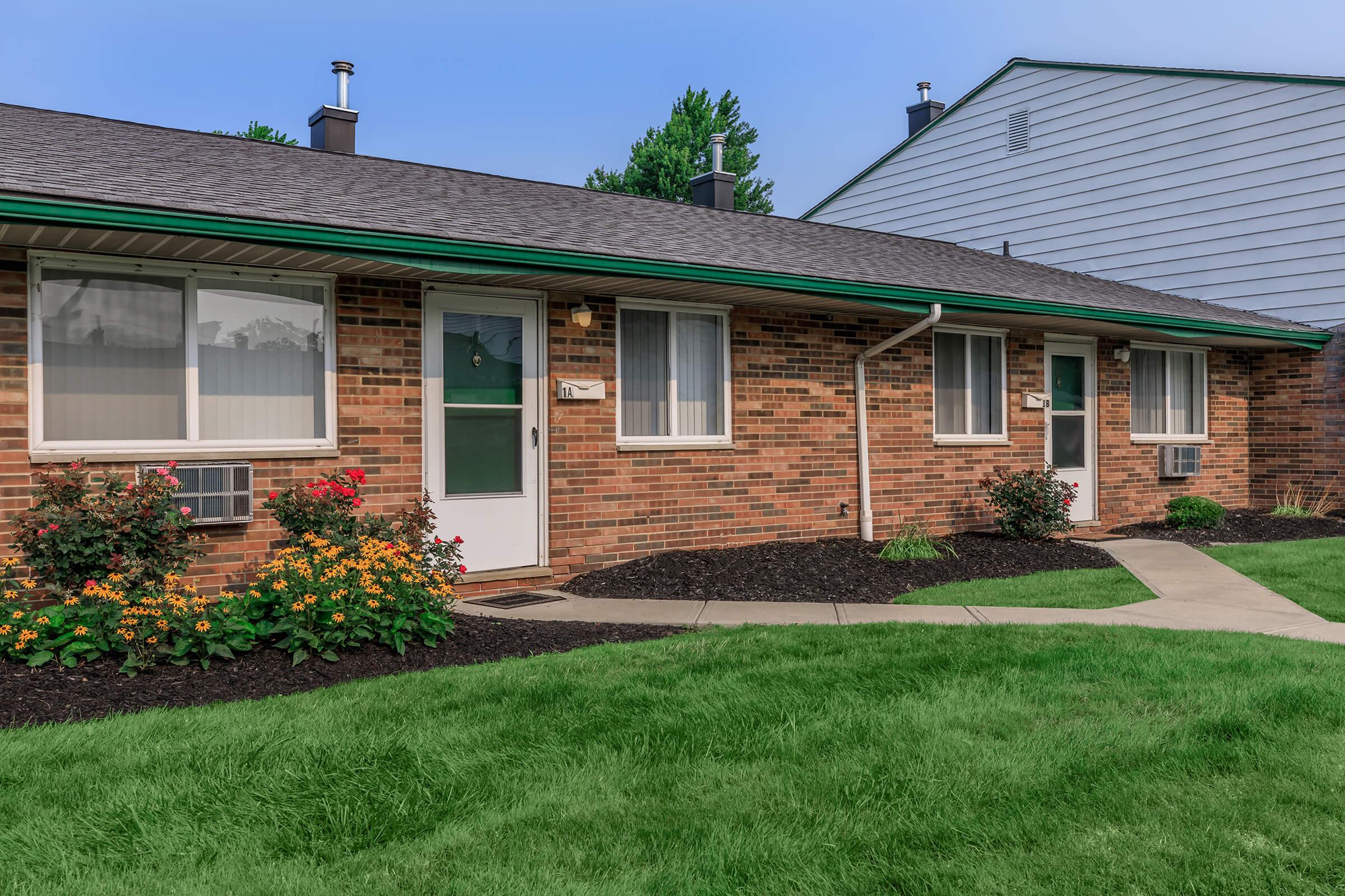 a large brick building with green grass in front of a house