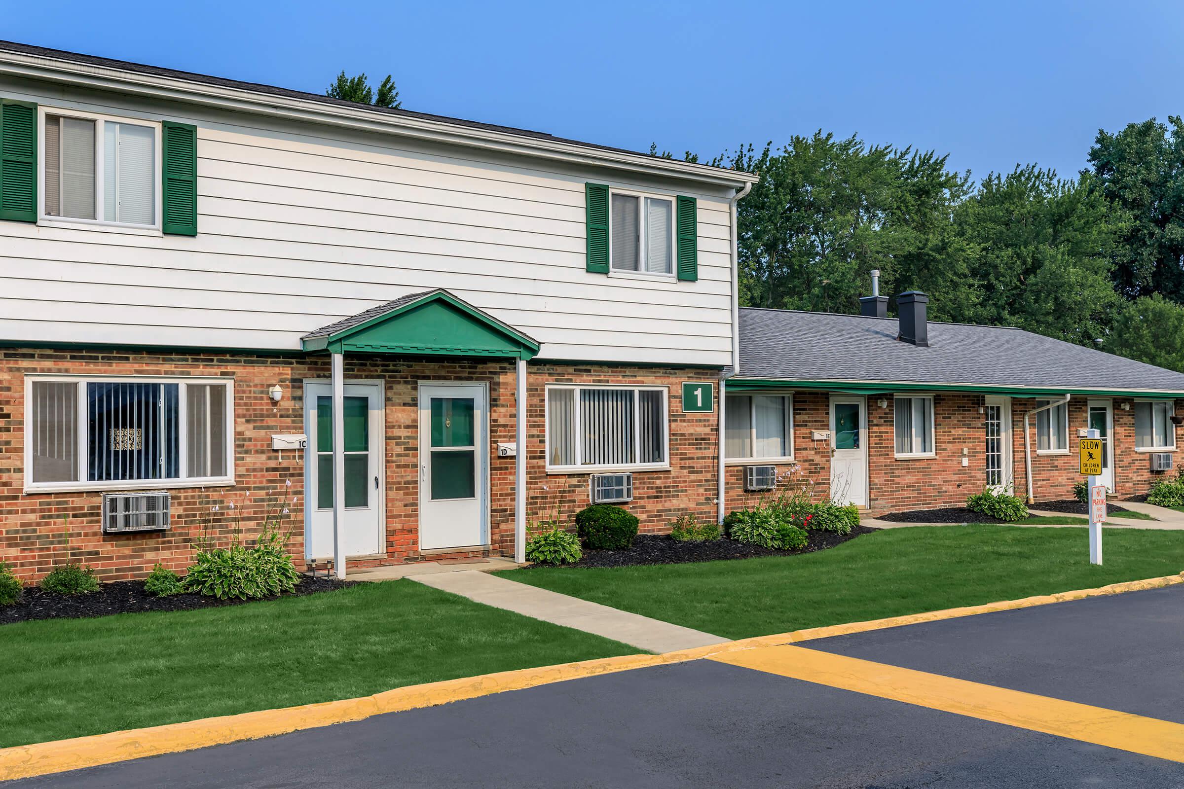 a large brick building with grass in front of a house