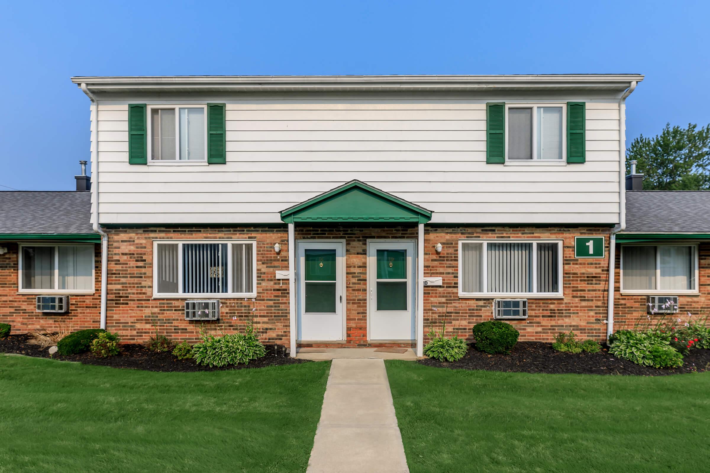 a house with a lawn in front of a brick building