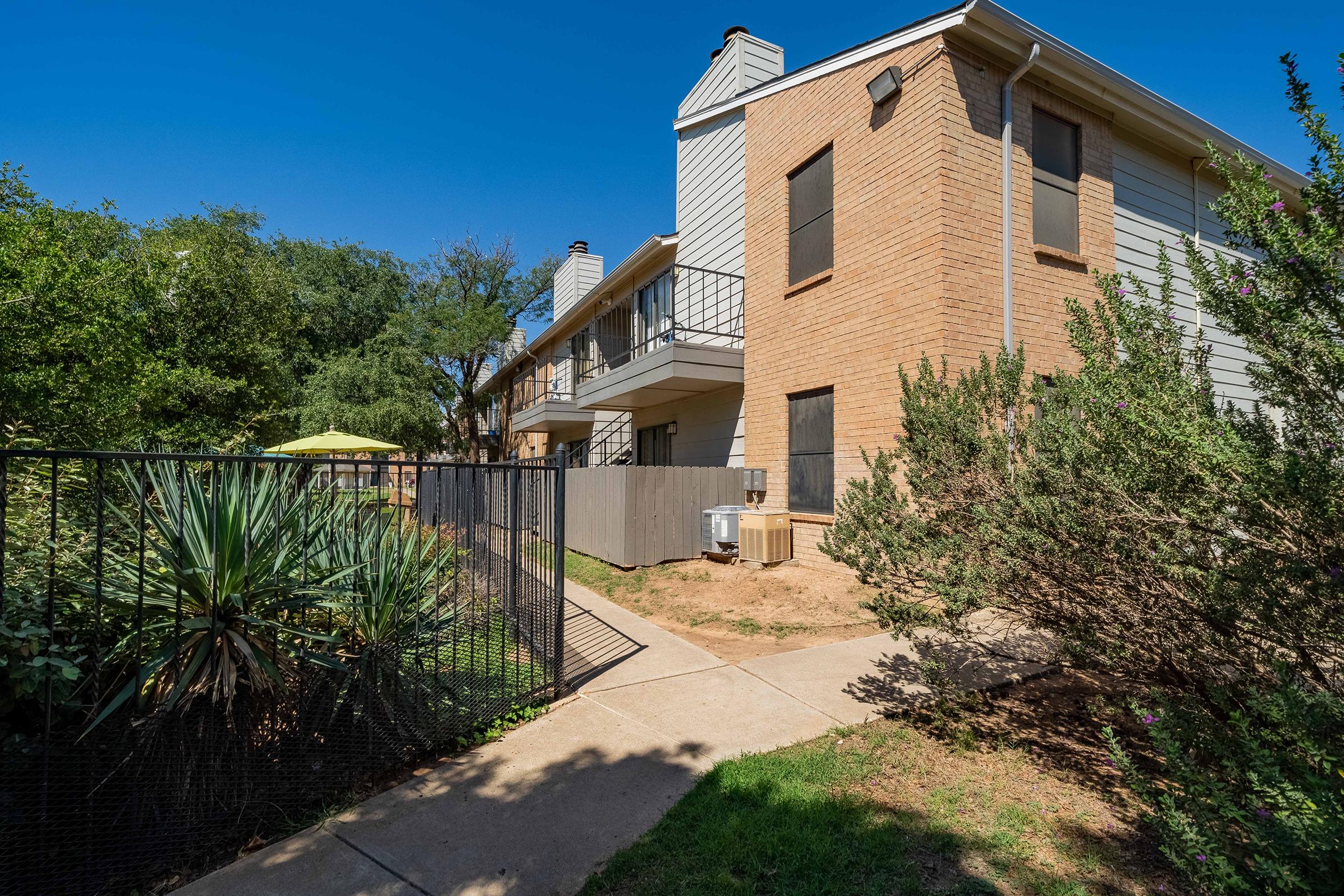 a house with bushes in front of a brick building