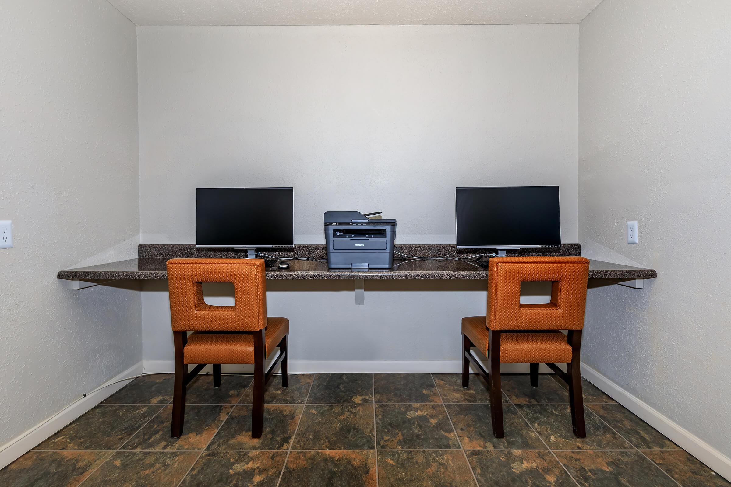 a desk with a computer and a chair in a room