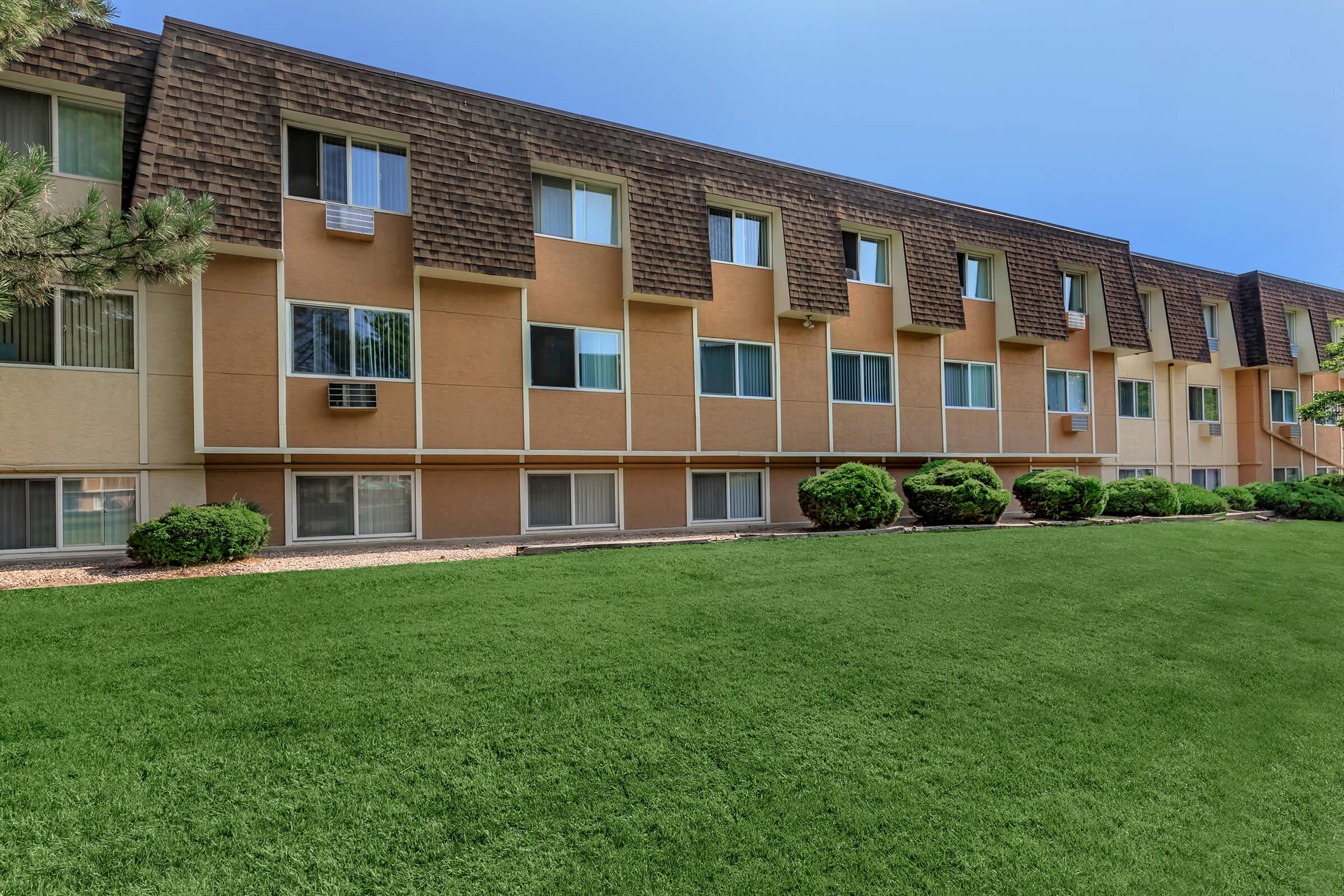 a large brick building with green grass in front of a house