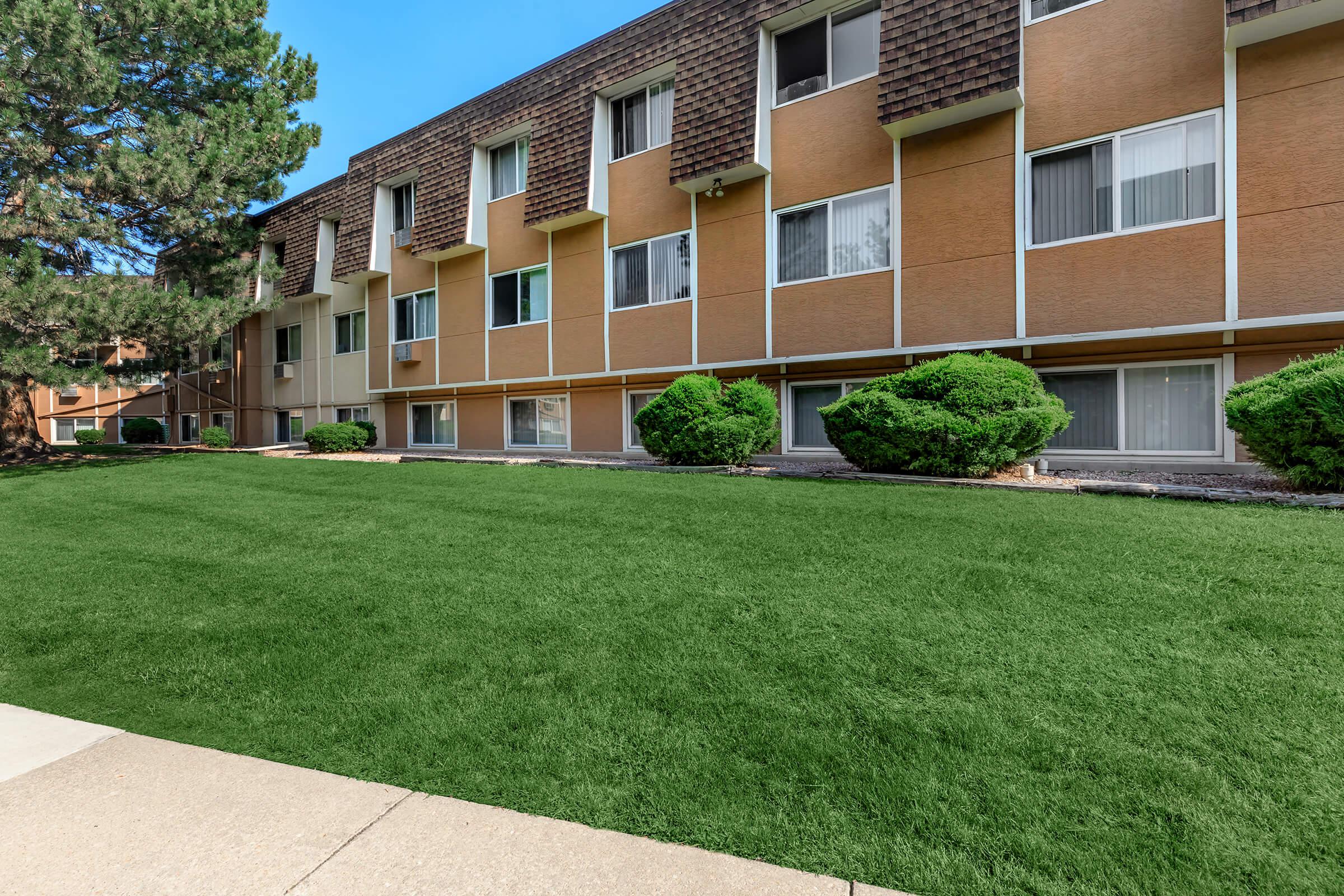 a large brick building with grass in front of a house