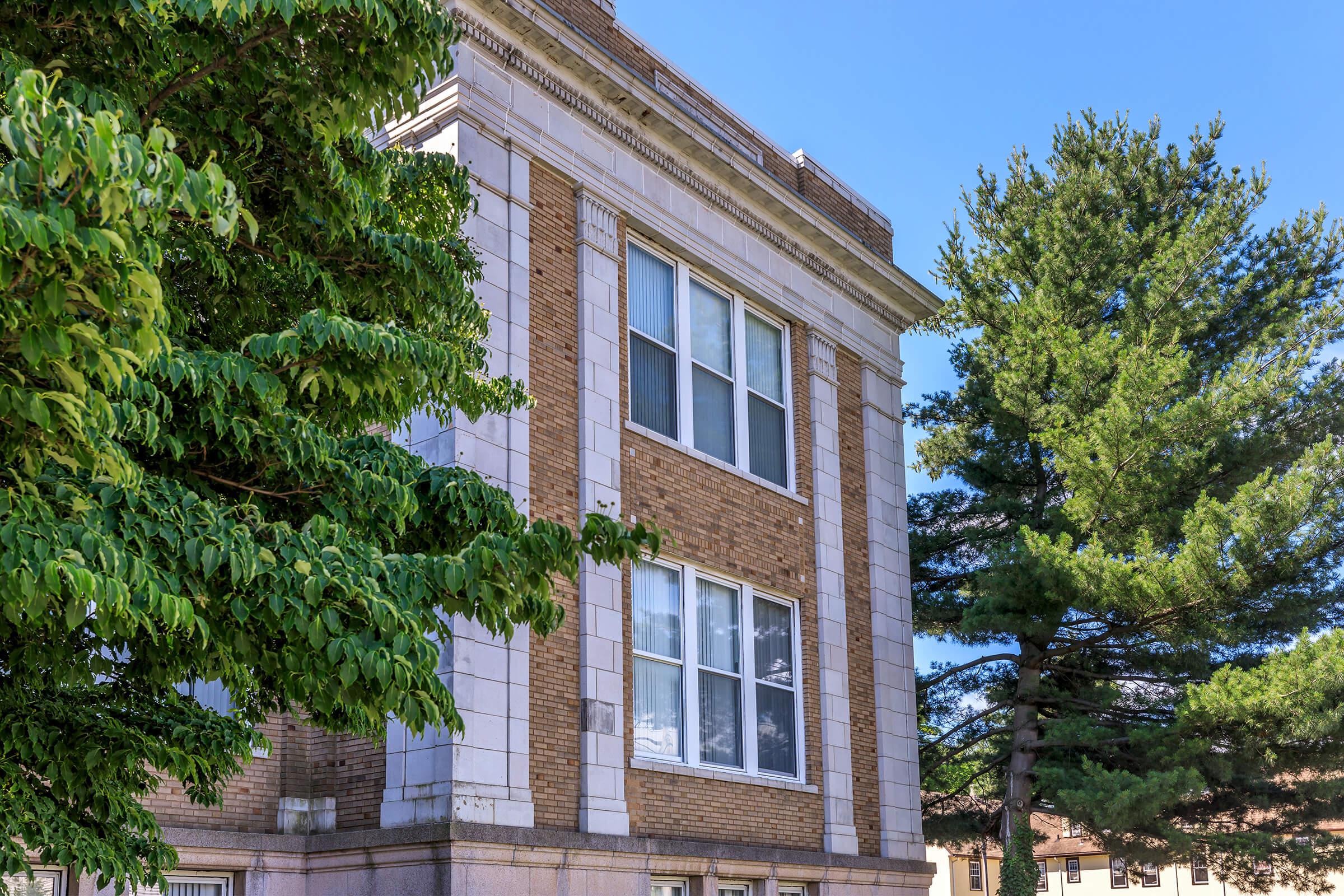 a tree in front of a brick building